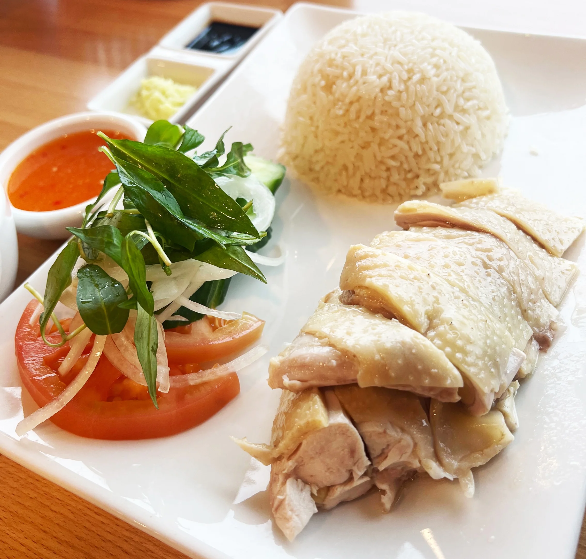 Hainanese chicken rice served with fresh herbs and chili sauce