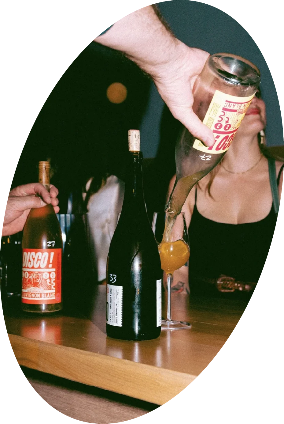 hand pouring natural wine oval