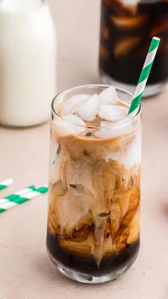 Rich espresso coffee topped with crema and surrounded by coffee beans