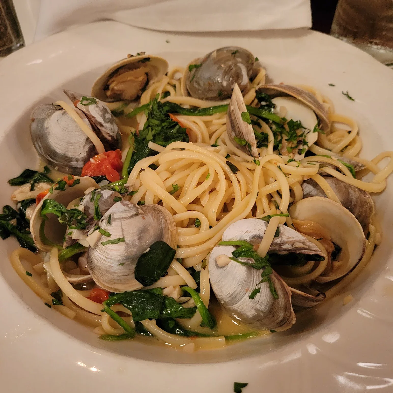 Spaghetti alle vongole with clams and herbs in a white bowl