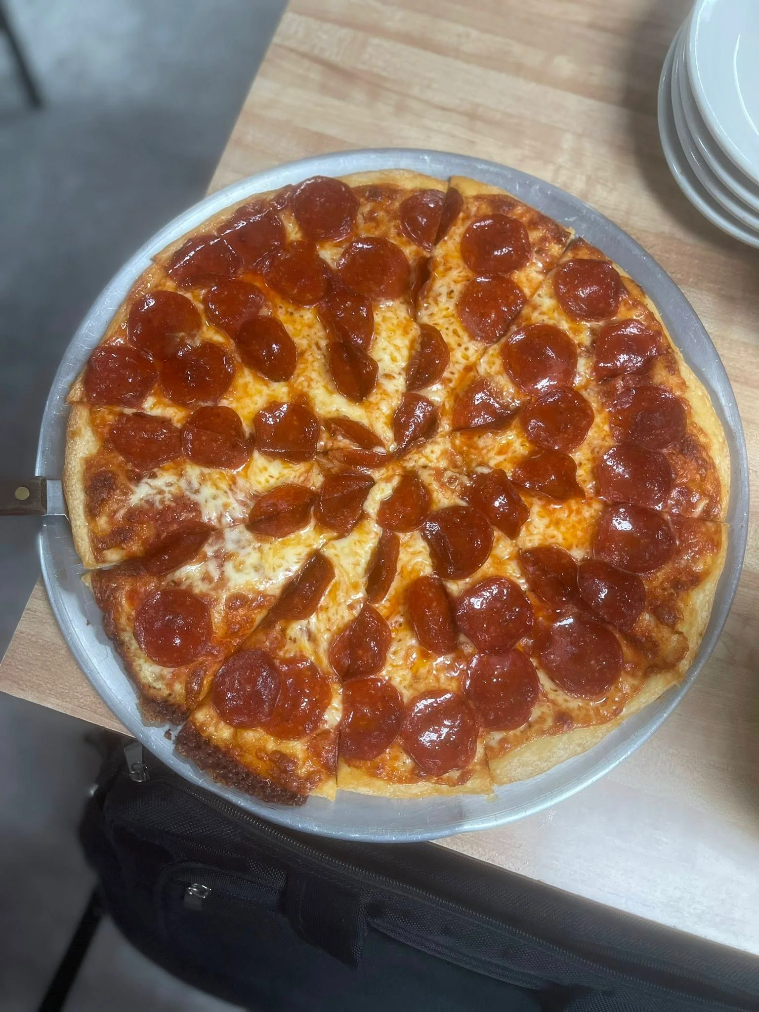 A large pepperoni pizza cut into slices, showcasing melted cheese and crispy pepperoni on a golden crust.