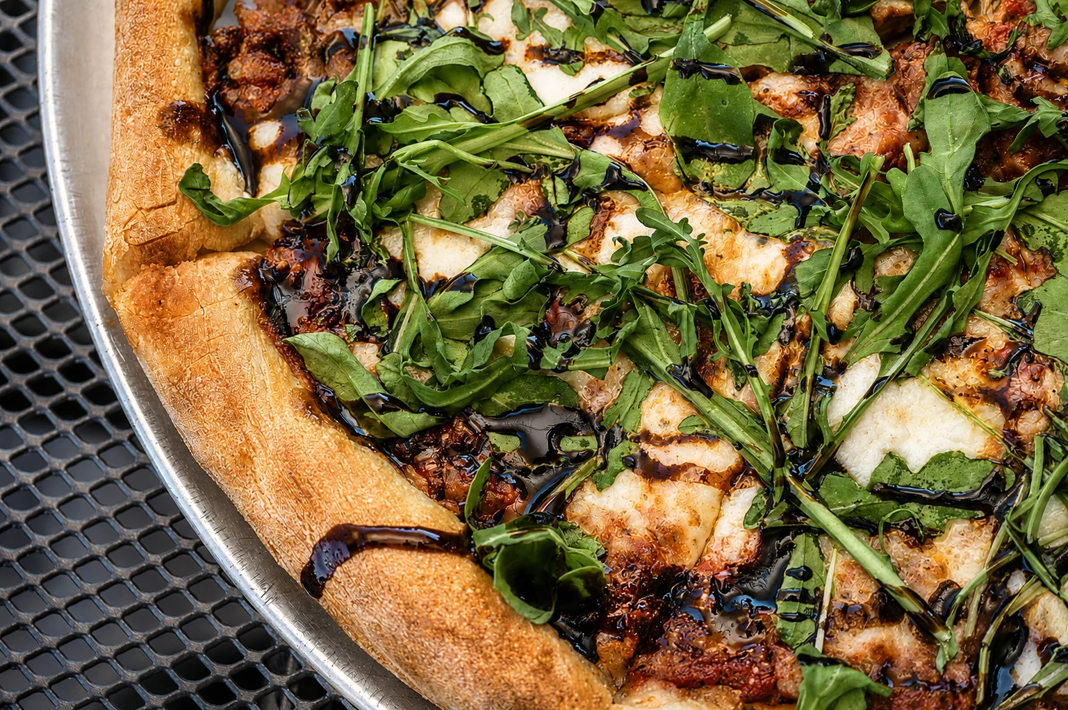 Gourmet pizza topped with fresh arugula and balsamic glaze