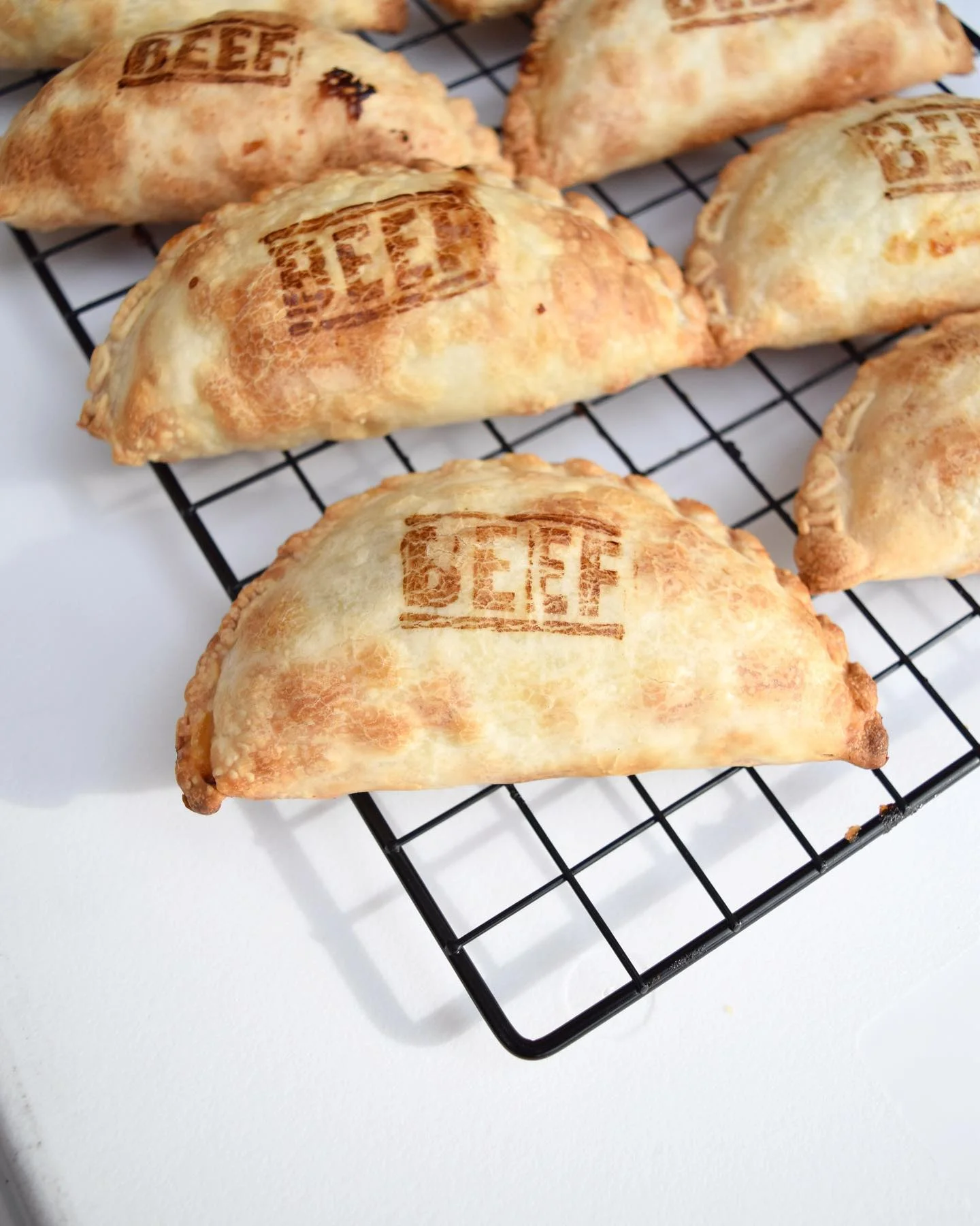 Golden beef empanadas cooling on a wire rack