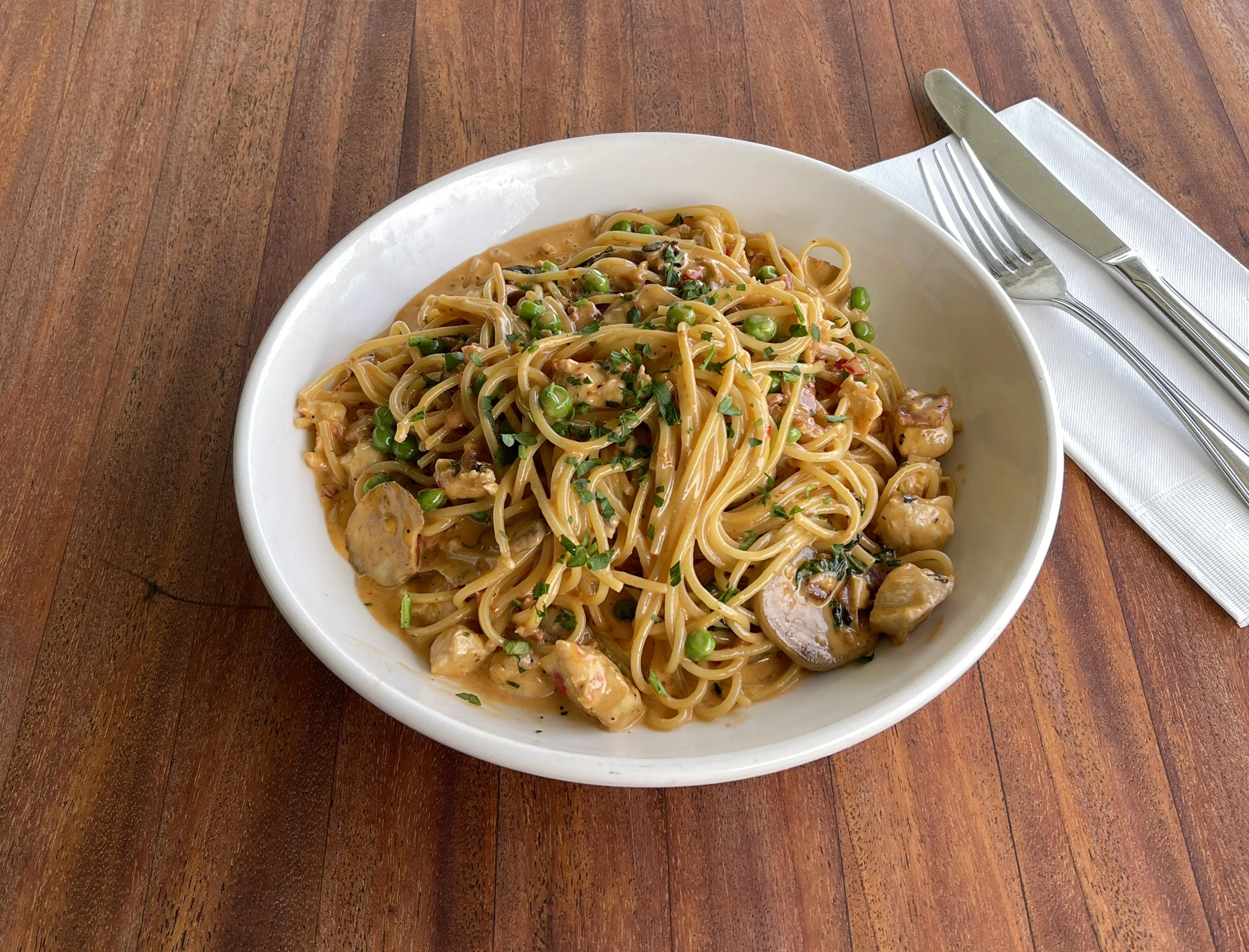 Creamy Italian linguine with peas and chicken on a white plate