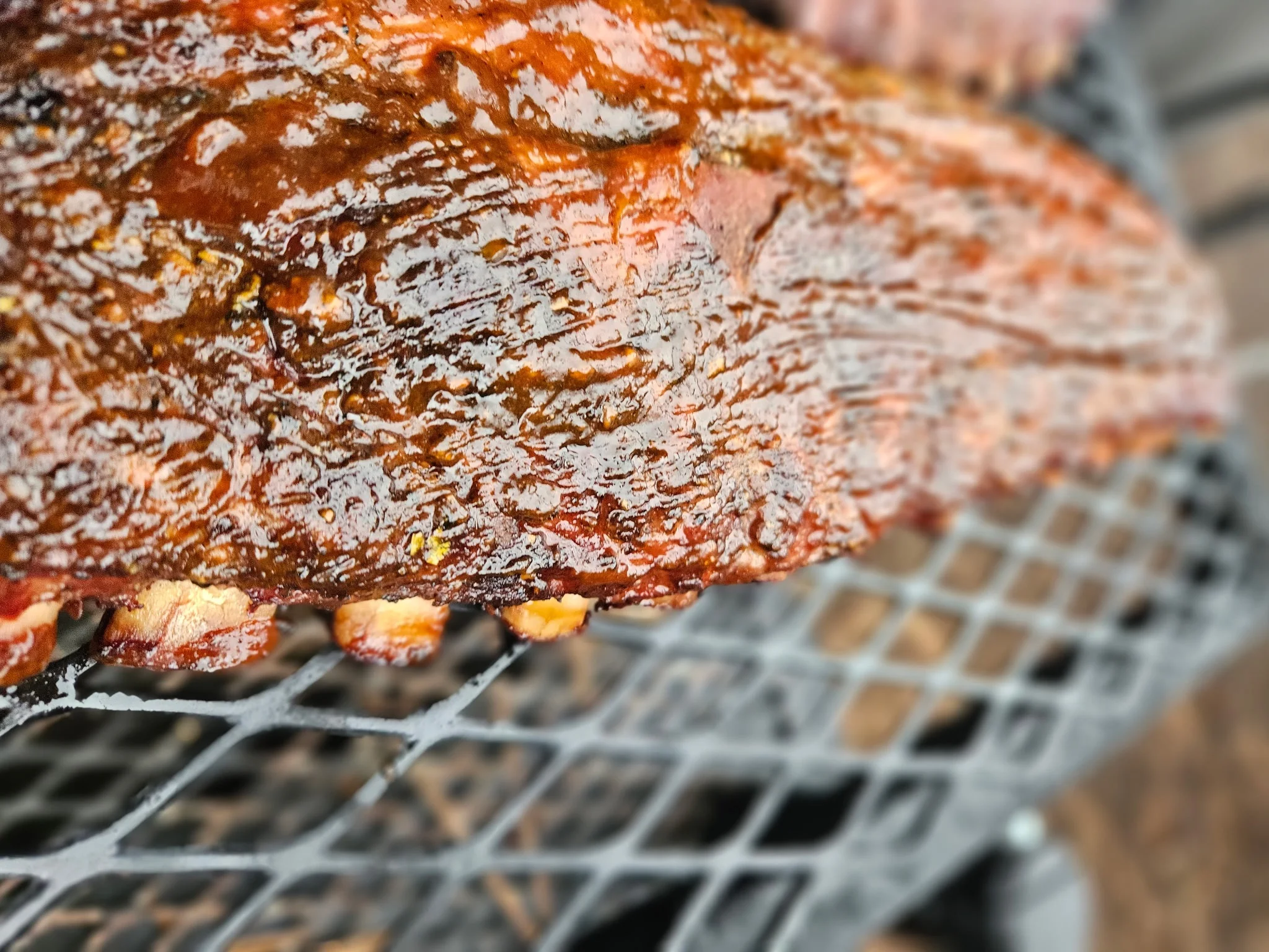 Smoked barbecue ribs glistening with sauce on a grill