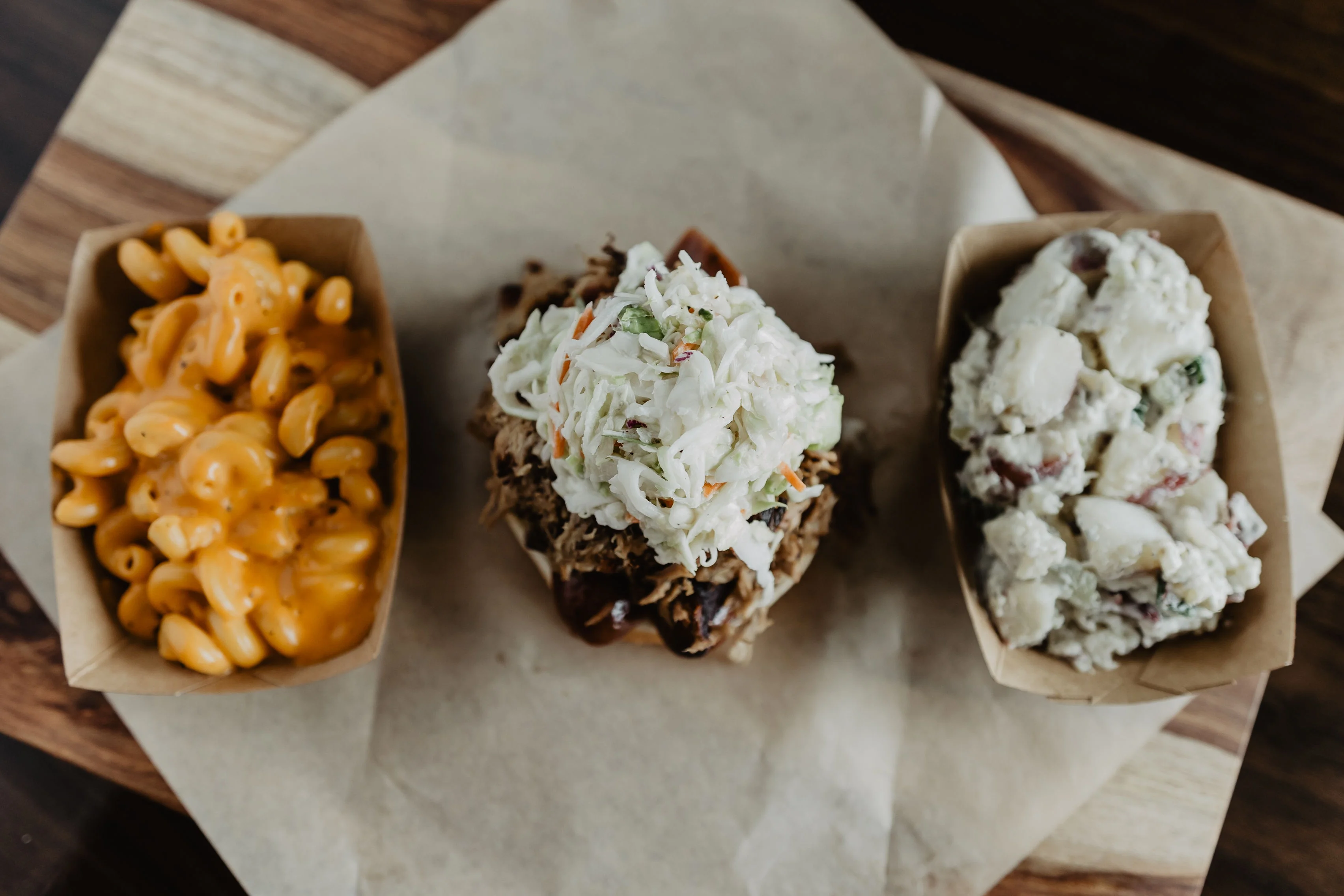 Pulled pork sandwich with coleslaw and sides of mac and potato salad