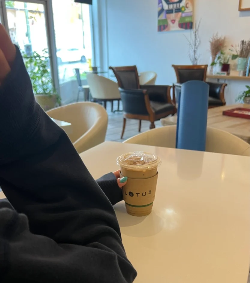 Women with an iced coffee and her yoga mat in the other chair