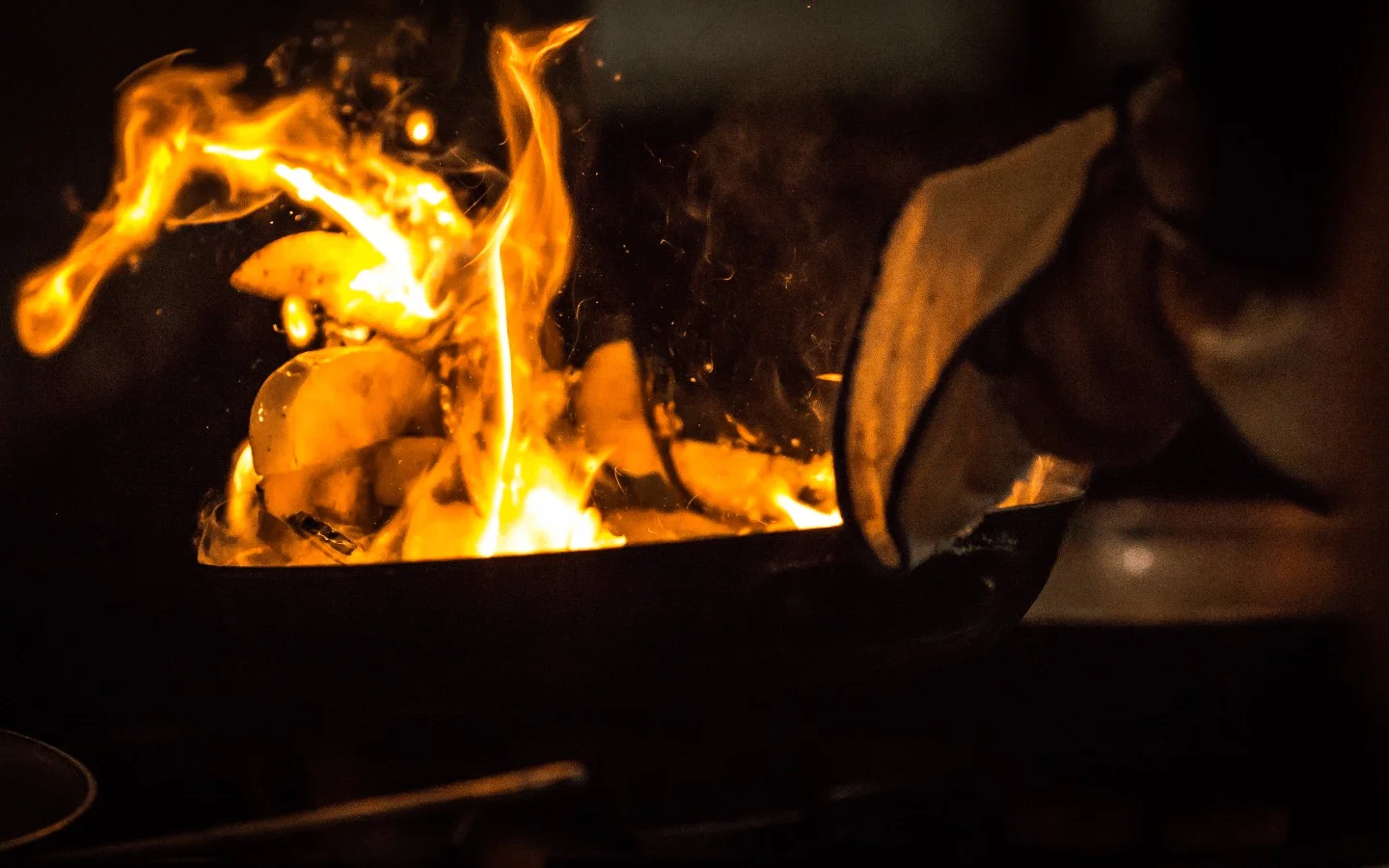 Flambé cooking technique with sizzling ingredients in a pan