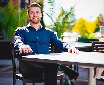 Smiling man seated at a restaurant table outdoors