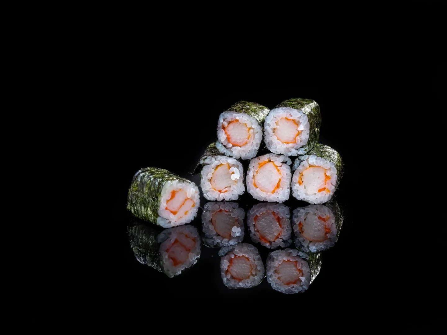 Japanese sushi rolls arranged on a reflective surface
