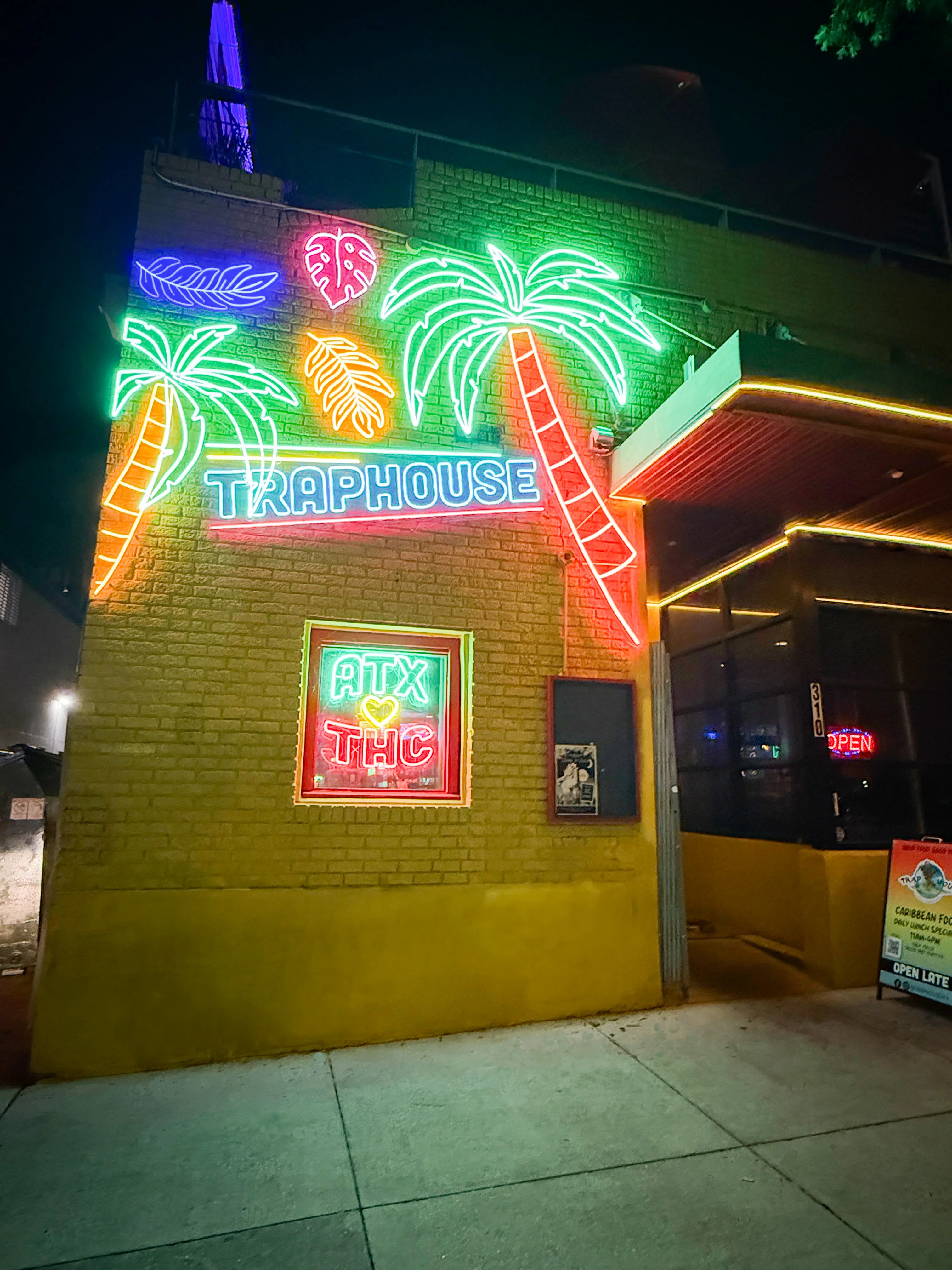 Vibrant neon sign of a restaurant named TrapHouse at night