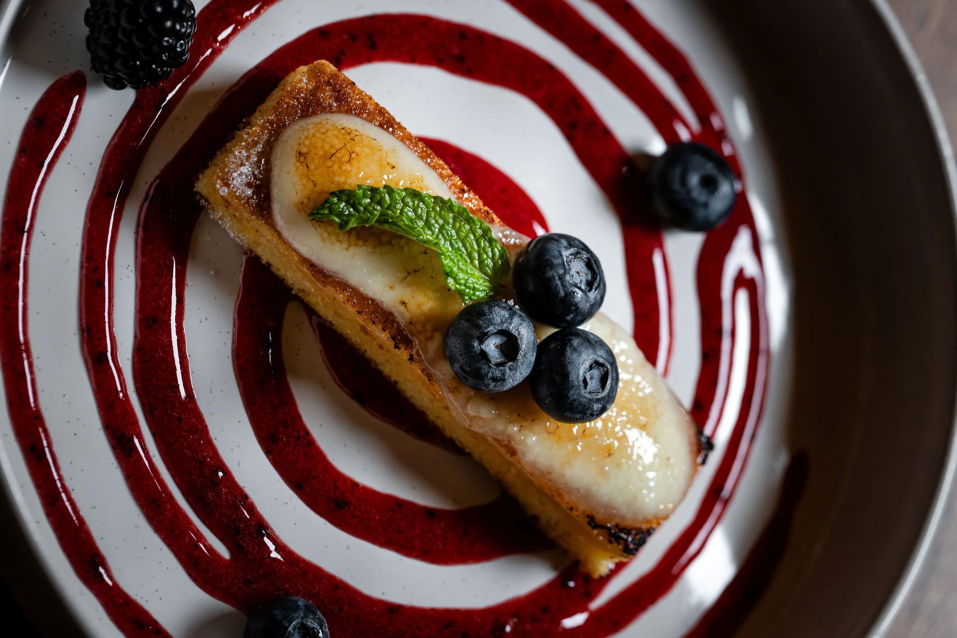 Delicious blueberry tart with berry sauce and mint garnish
