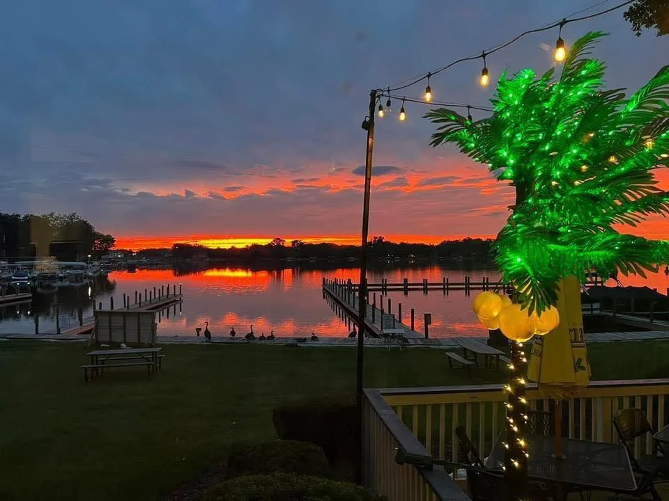 Scenic sunset over a marina with glowing palm tree decorations