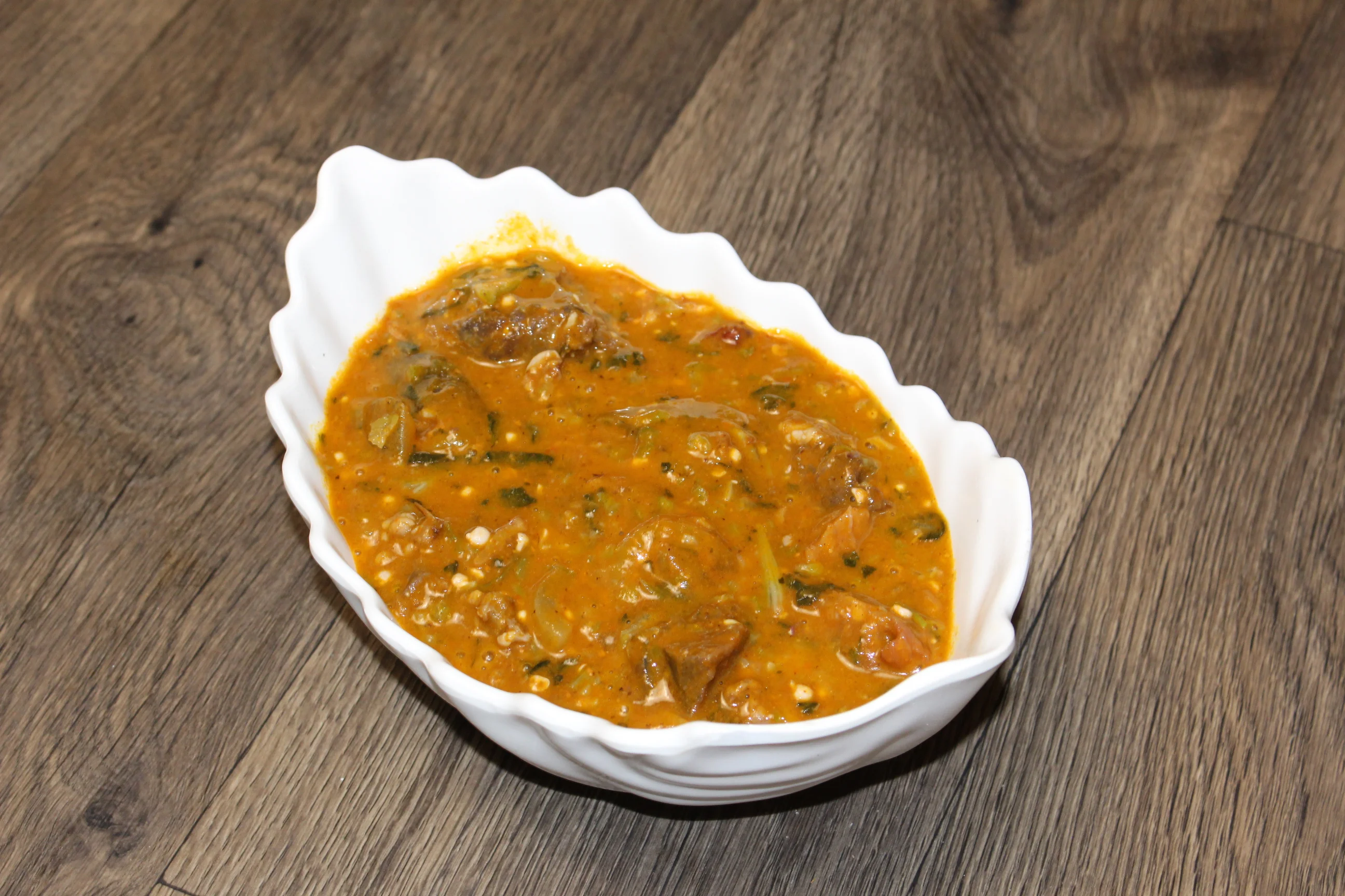 Nigerian egusi soup served in a white bowl