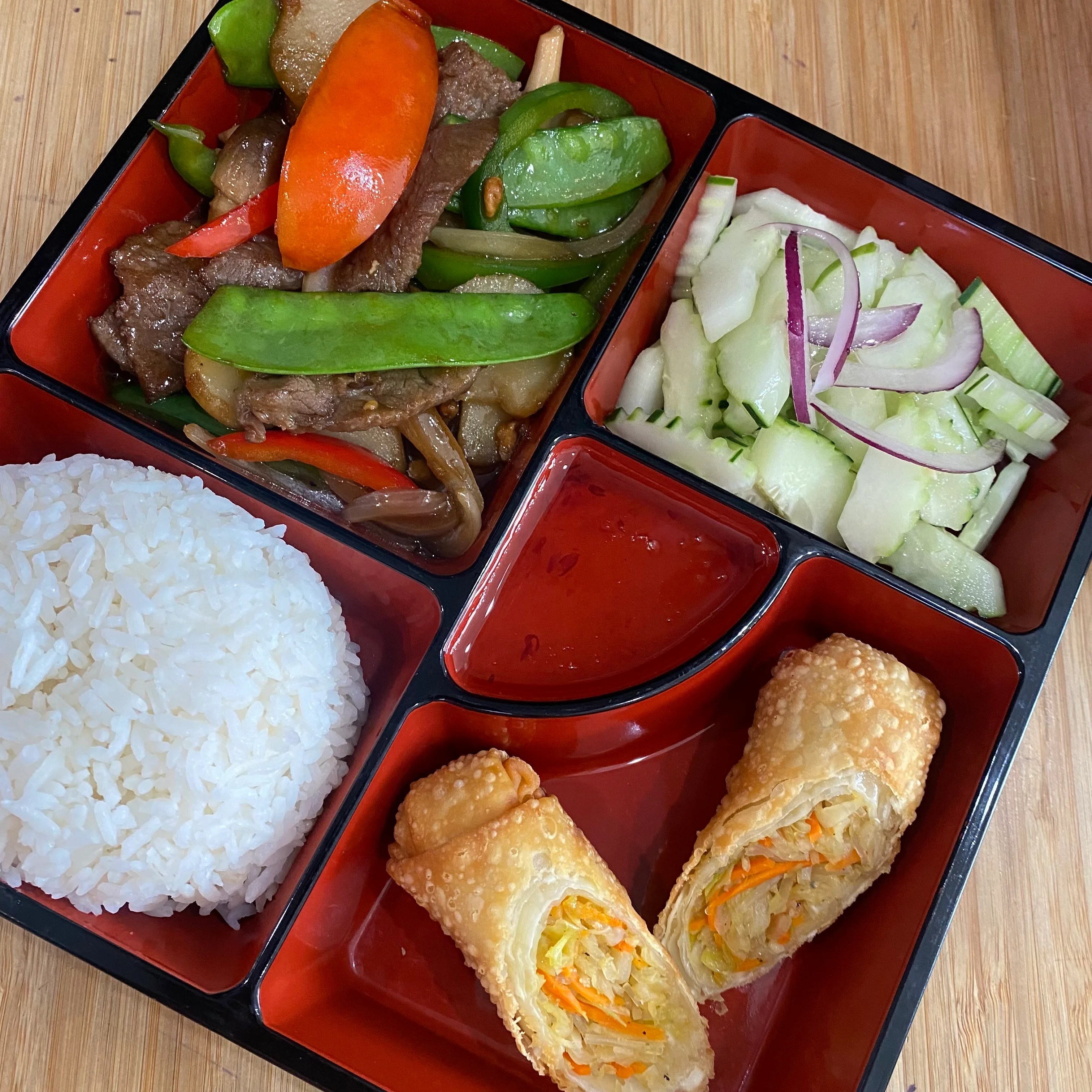 Chinese beef stir-fry bento box with rice and spring rolls