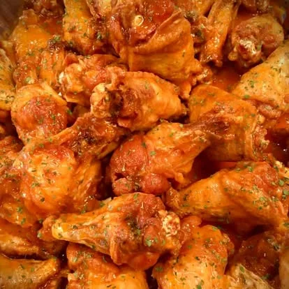 Spicy buffalo chicken wings garnished with herbs