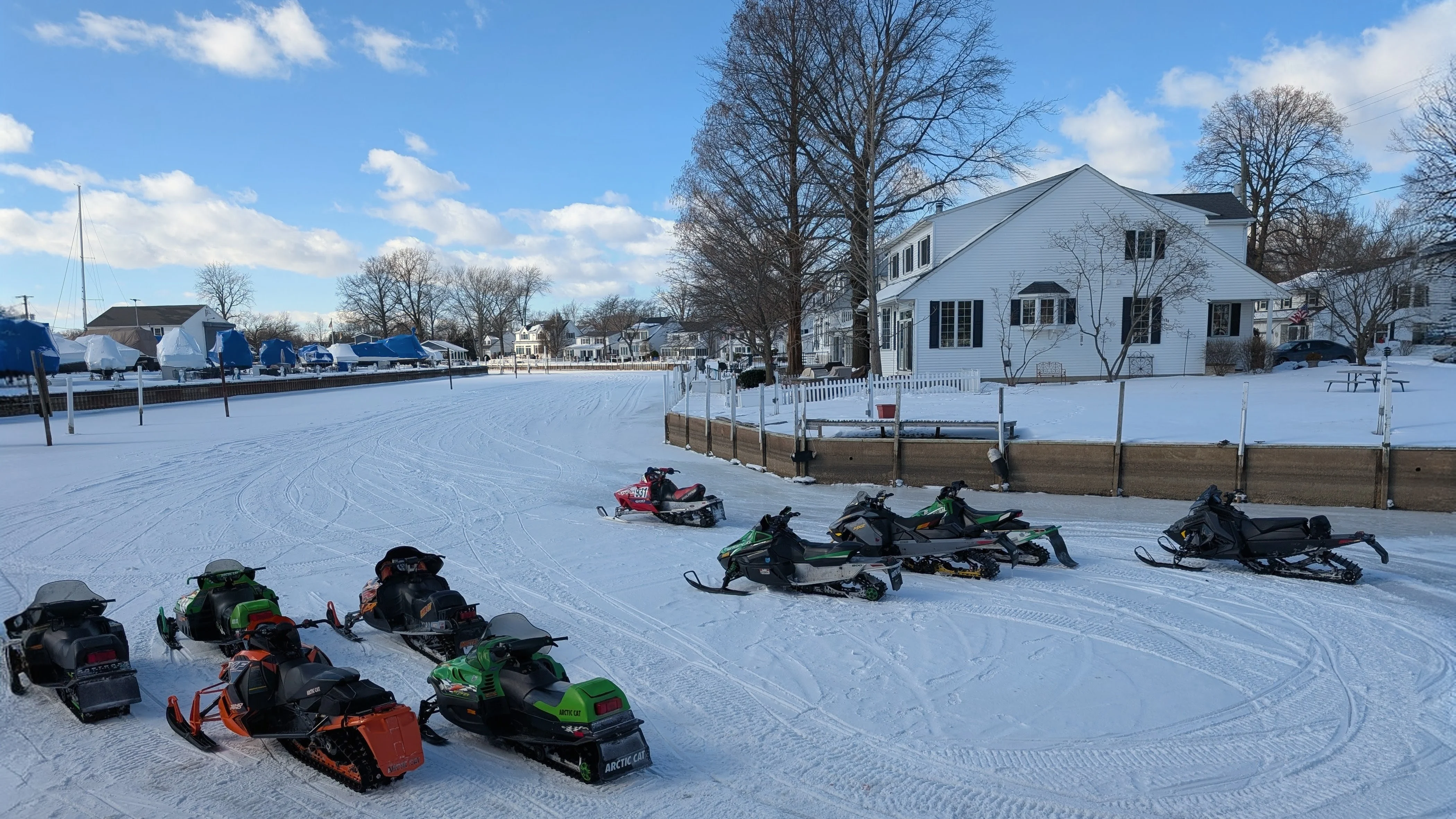 Snowmobiles parked on a snowy landscape near a residential area