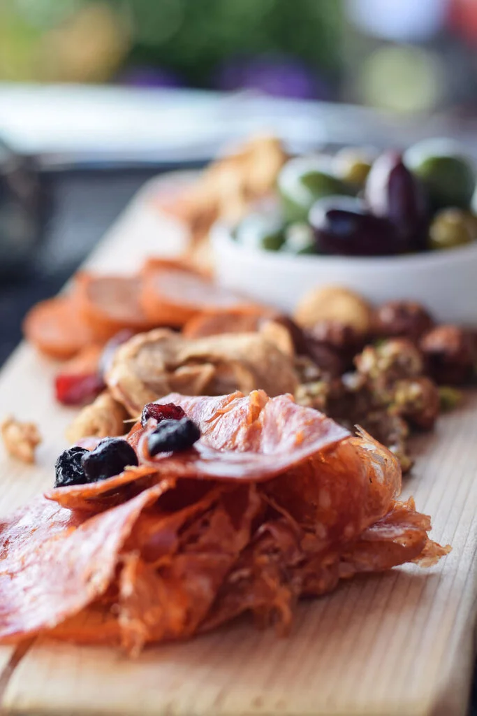 A charcuterie board featuring assorted cured meats, dried fruits, and olives elegantly arranged.