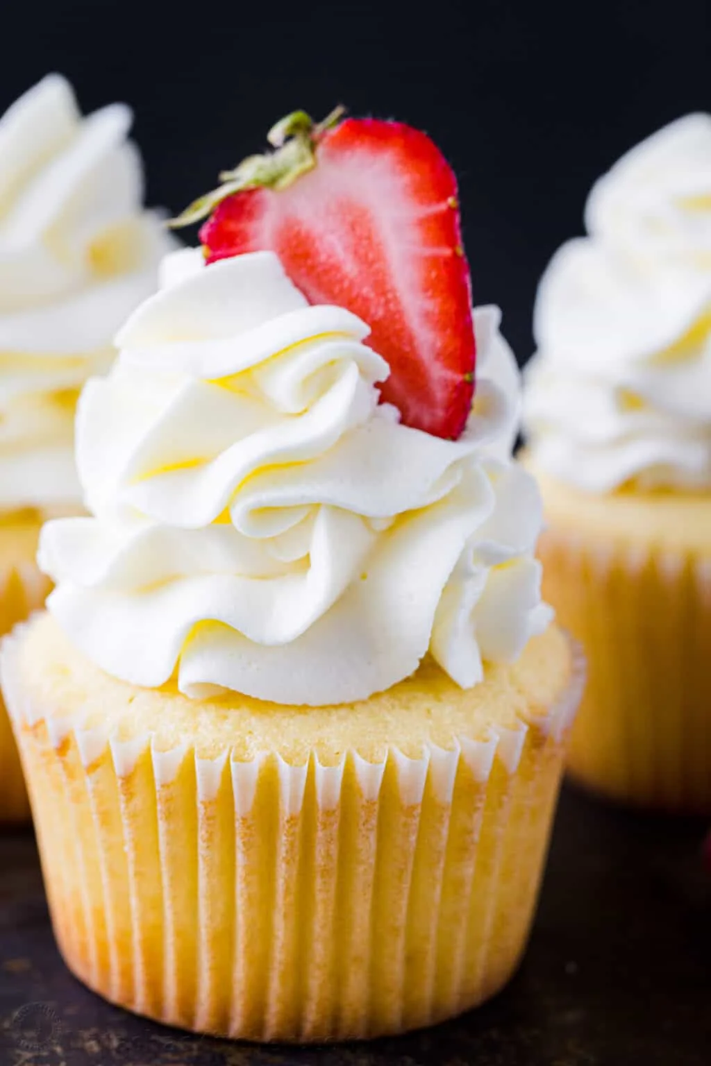 Delicious vanilla cupcake topped with whipped cream and fresh strawberry
