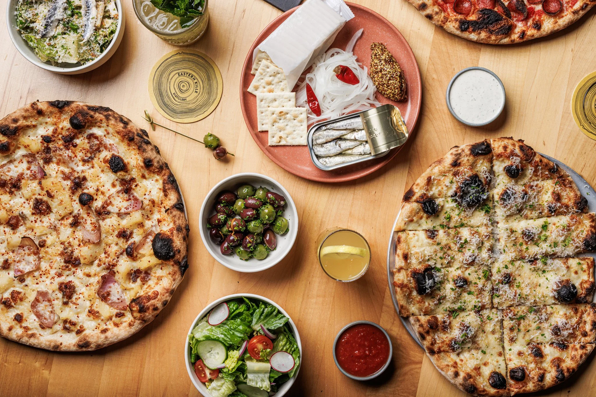 Artisan pizzas and Mediterranean appetizers on a wooden table