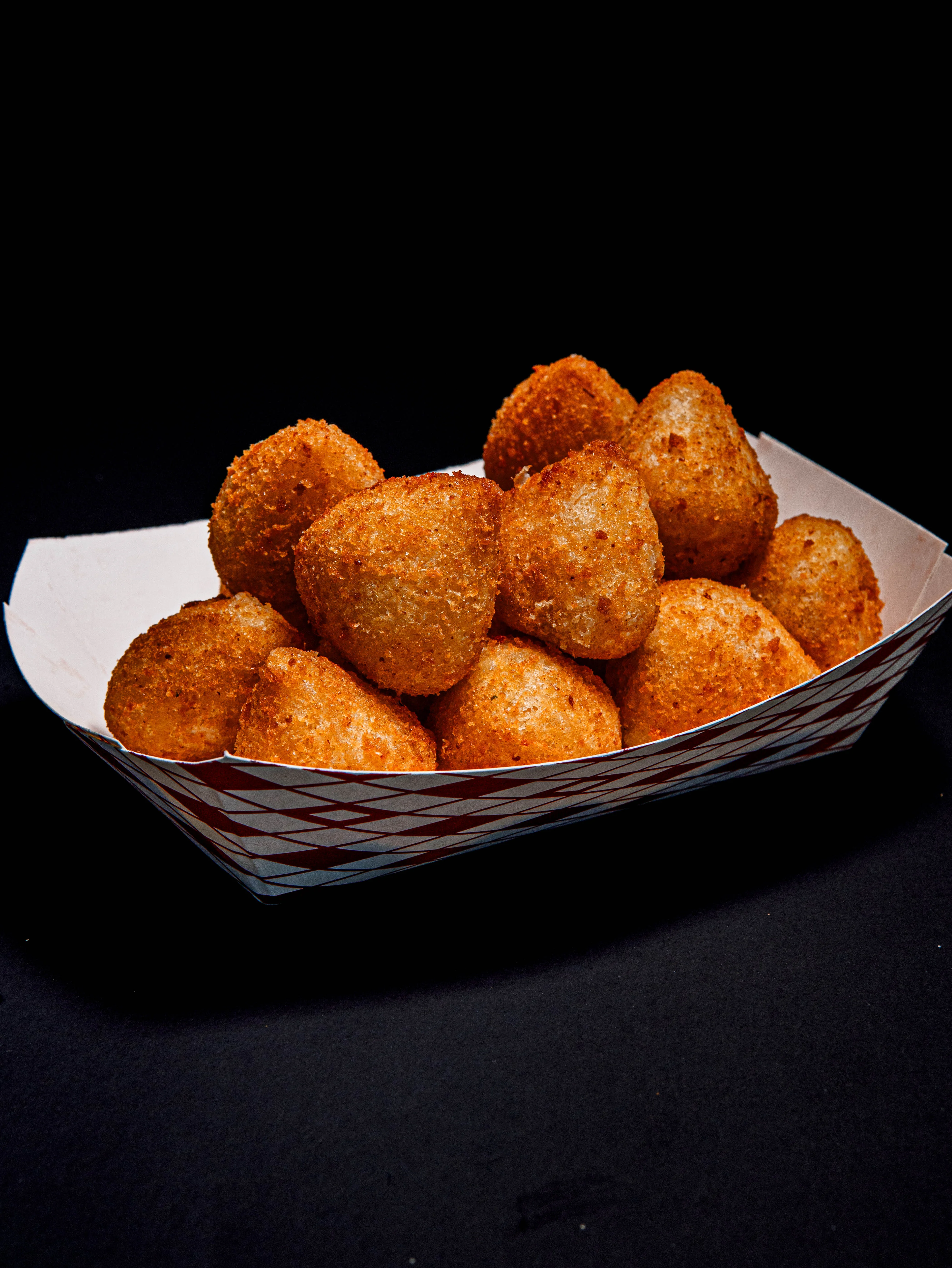 Crispy Brazilian coxinhas served in a paper tray