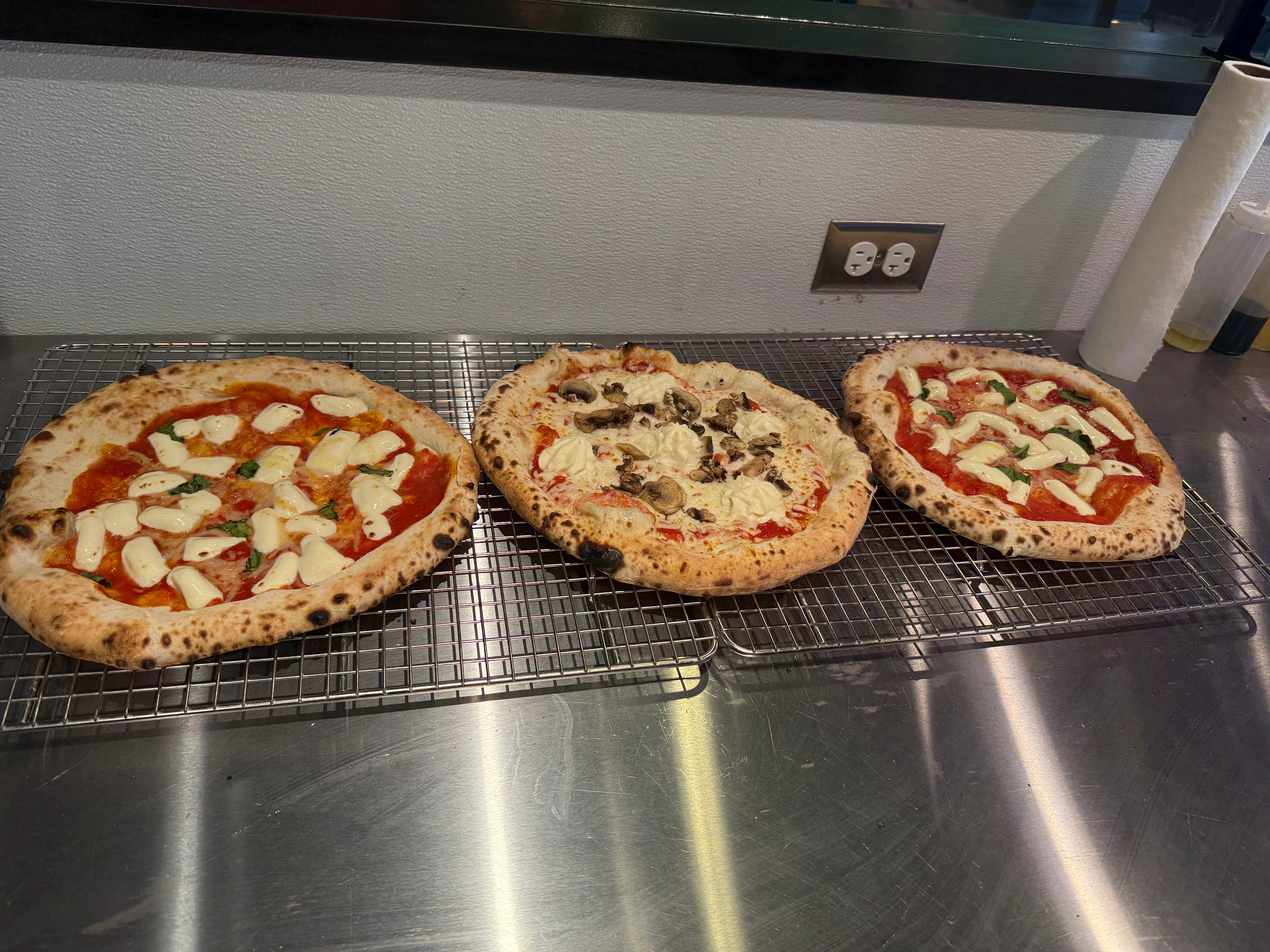 Three artisanal Neapolitan pizzas on a cooling rack