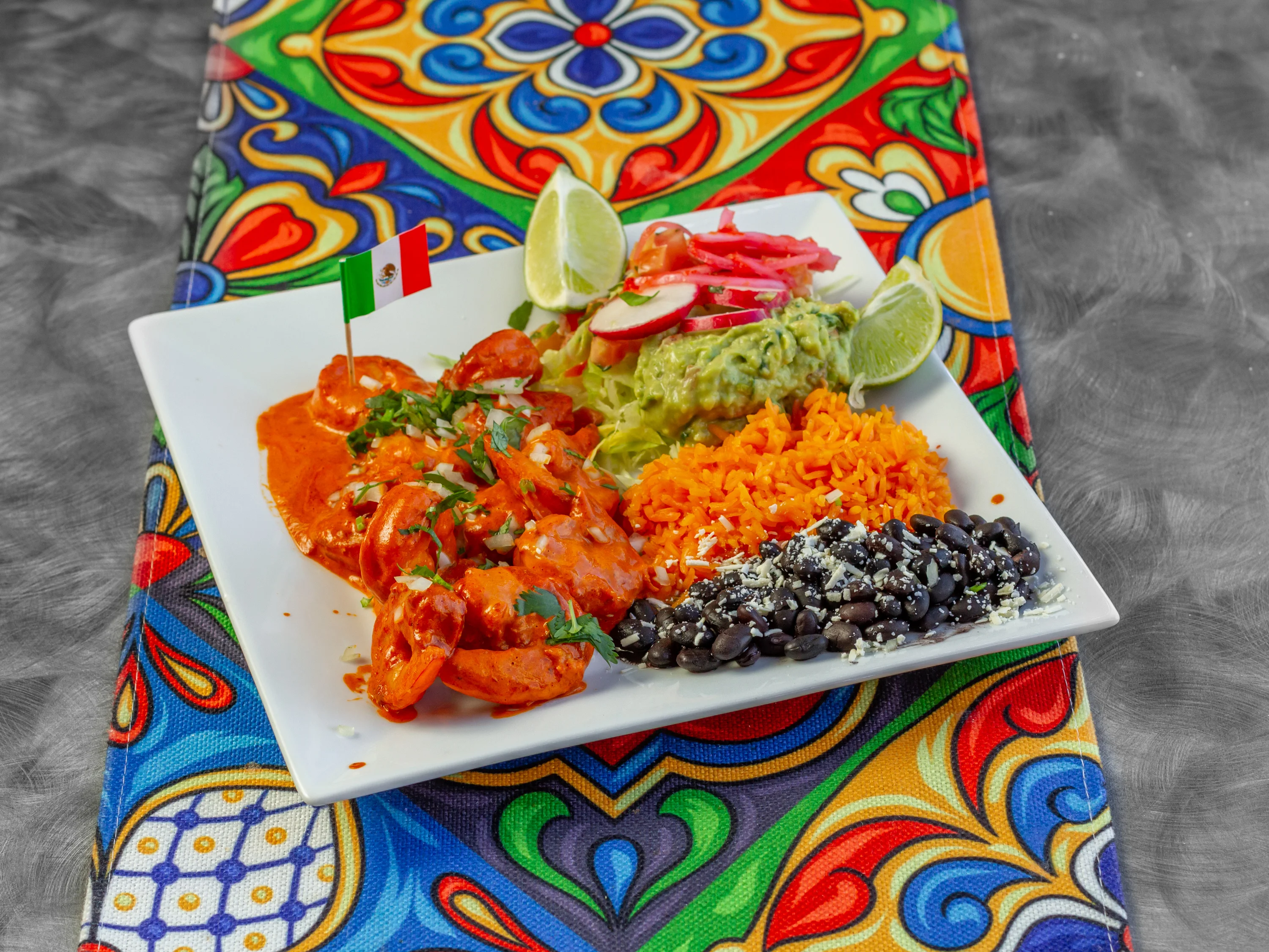 Shrimp enchiladas with rice and guacamole on a colorful plate