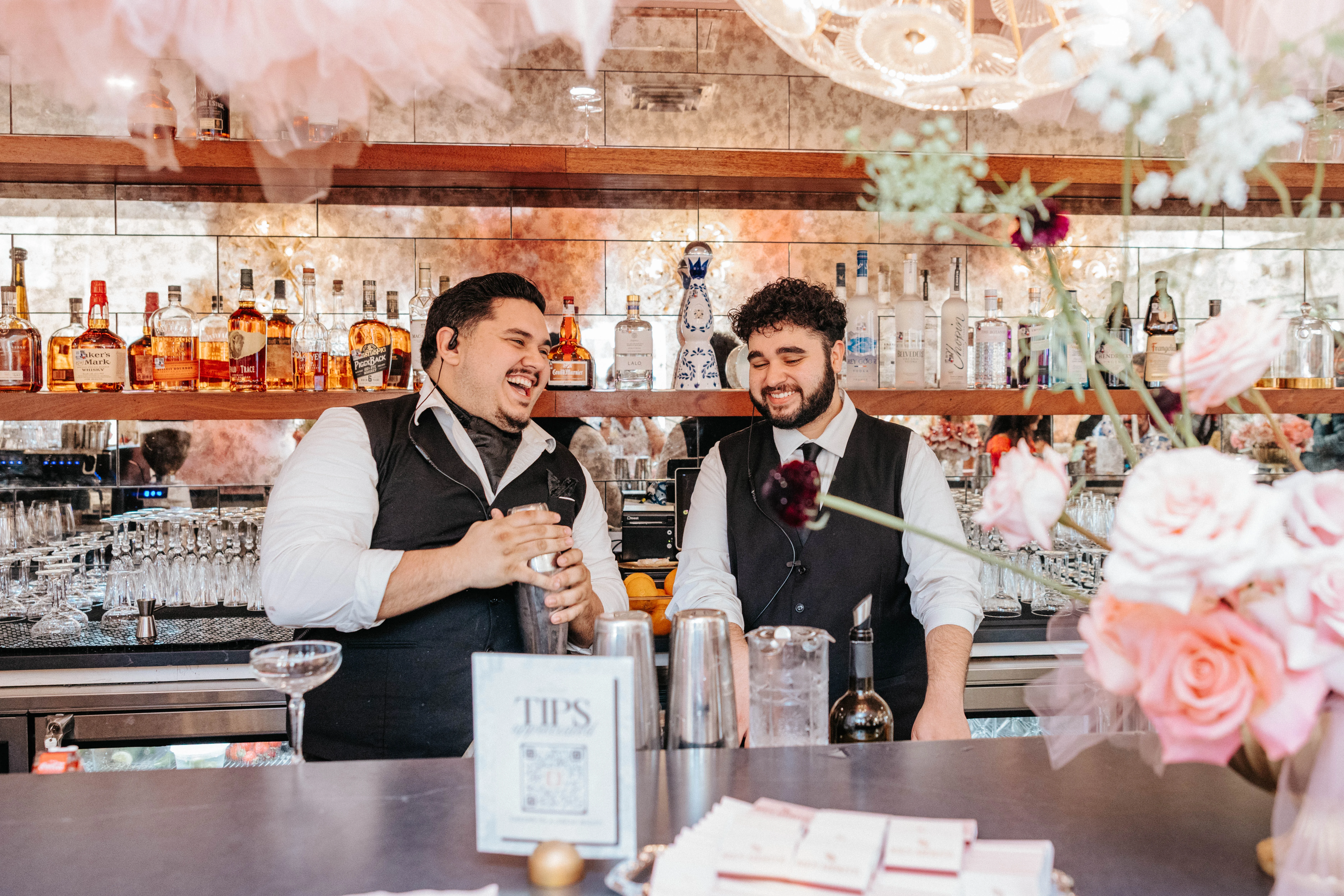 Bartenders laughing while mixing cocktails at a stylish bar