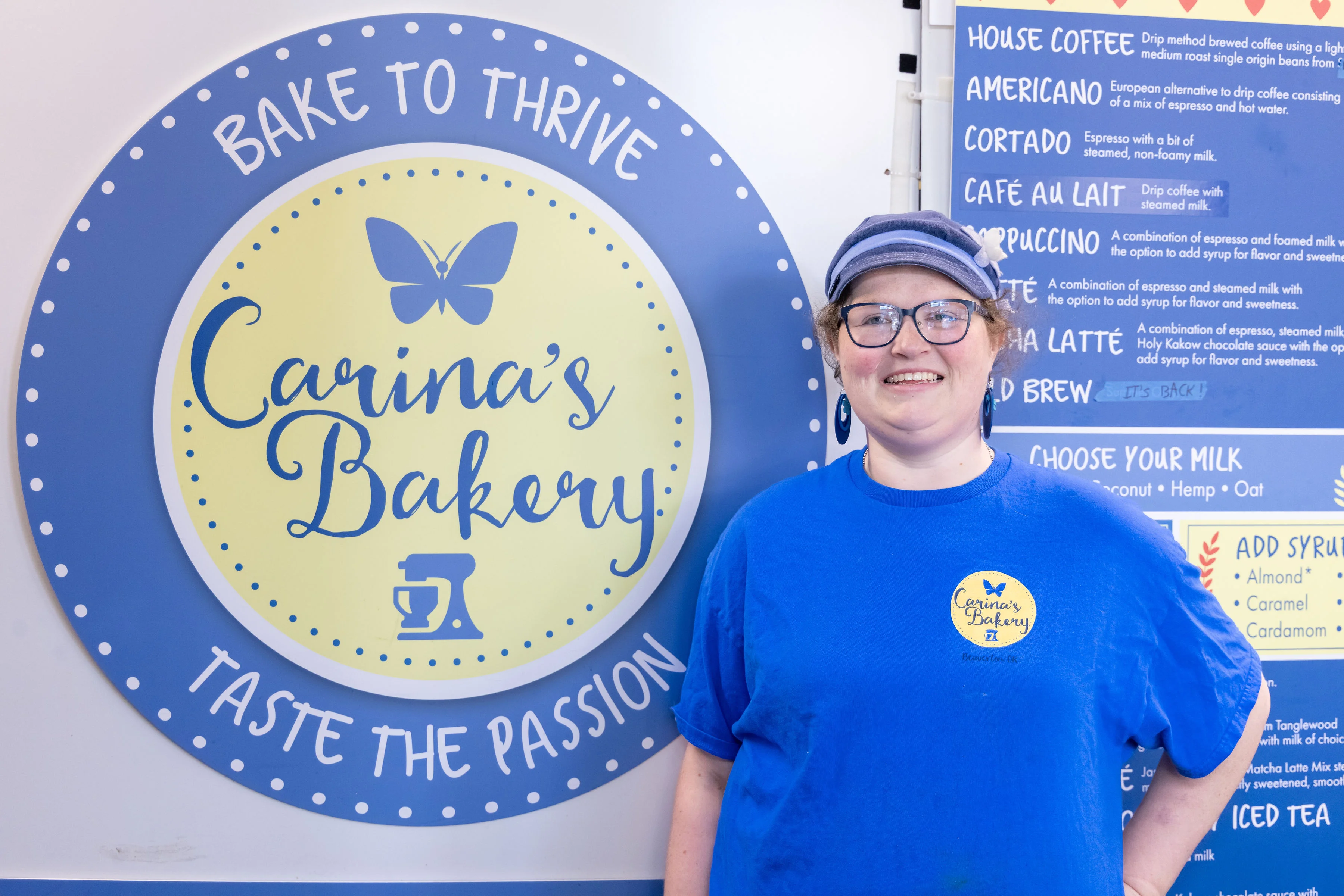 Employee at Carina's Bakery with logo backdrop