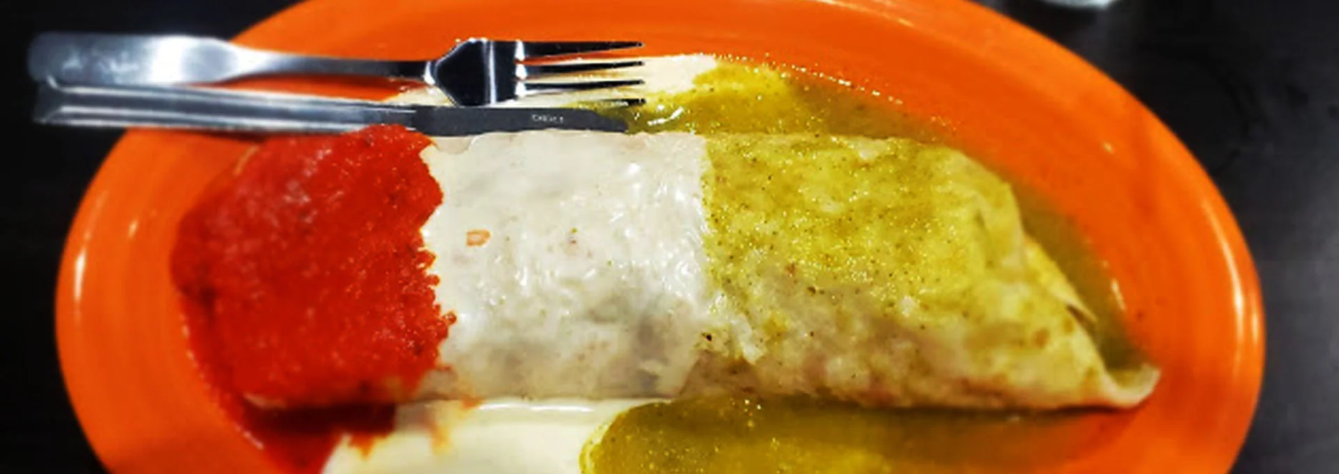 Enchiladas with red and green sauces on a vibrant plate