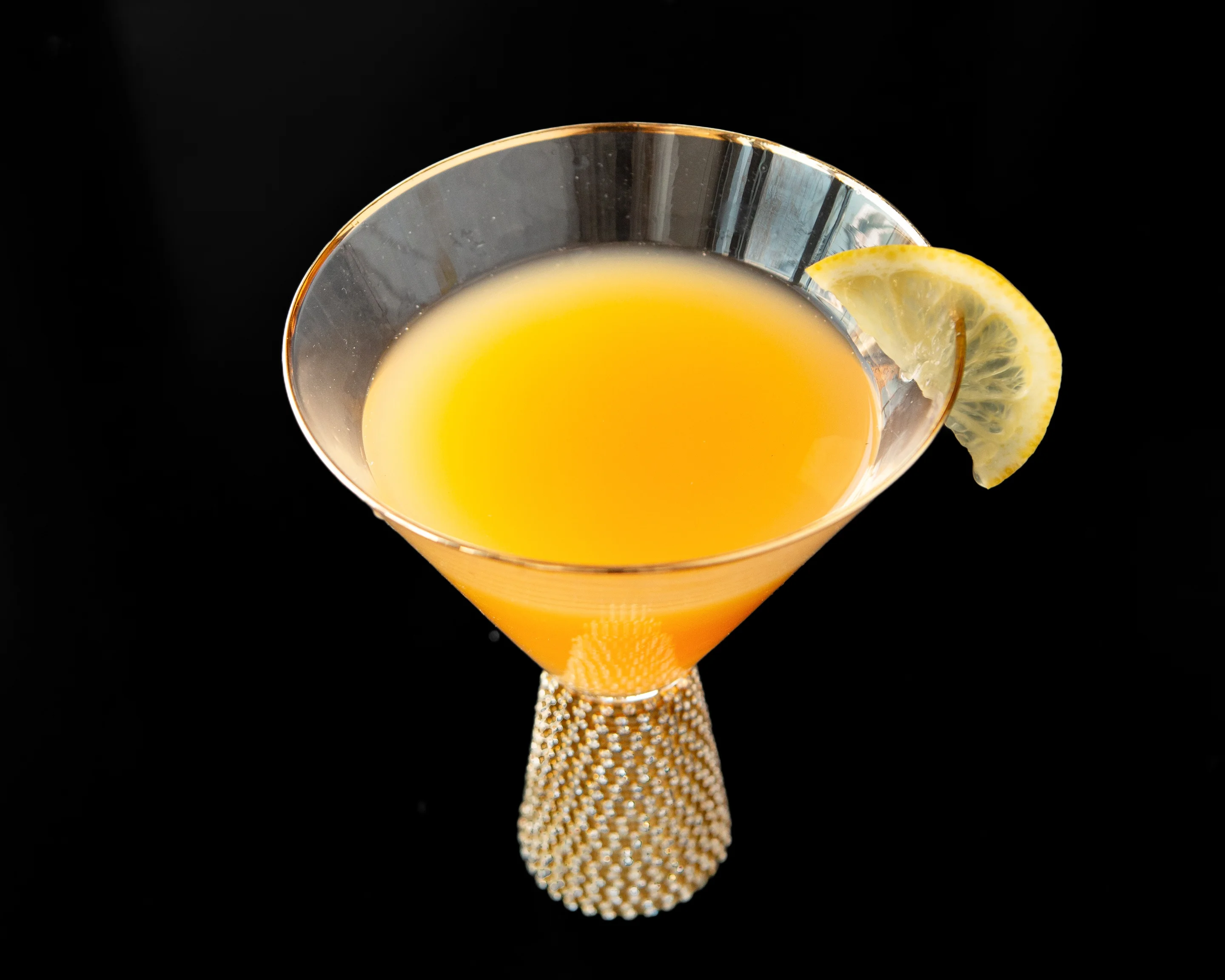 Vibrant orange cocktail garnished with lemon slice