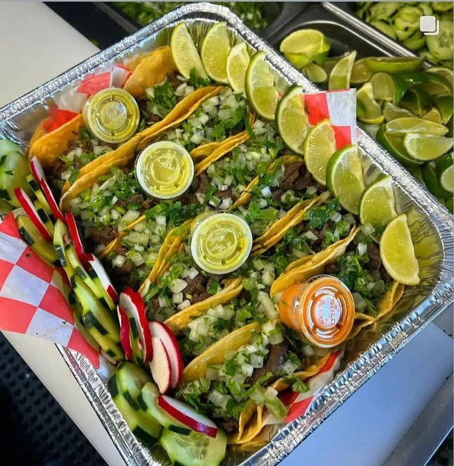 Colorful platter of street tacos with lime and fresh toppings