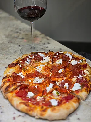 Pepperoni pizza with goat cheese and red wine