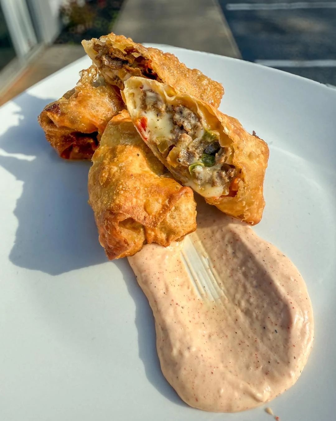 Crispy spring rolls stuffed with meat and vegetables, served with a creamy dipping sauce.