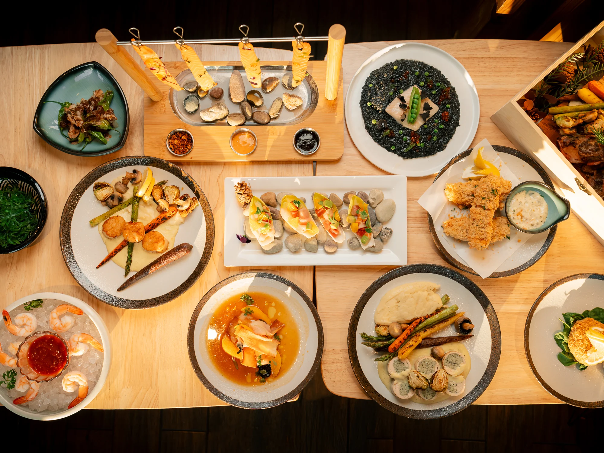 An array of gourmet dishes on a wooden table, showcasing seafood, vegetables, and unique preparations, creating a vibrant dining experience.