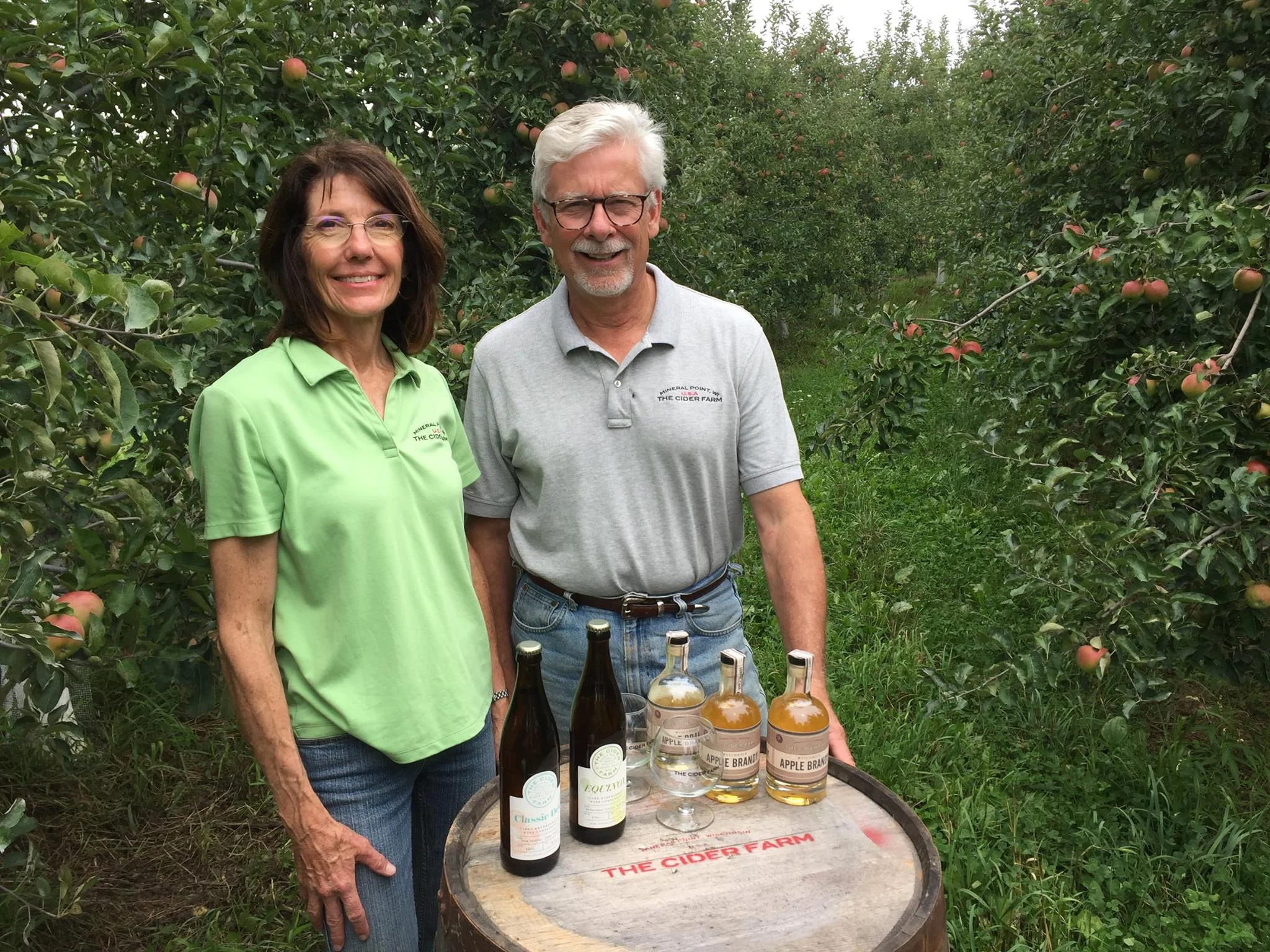Cider makers showcasing artisanal apple cider in an orchard