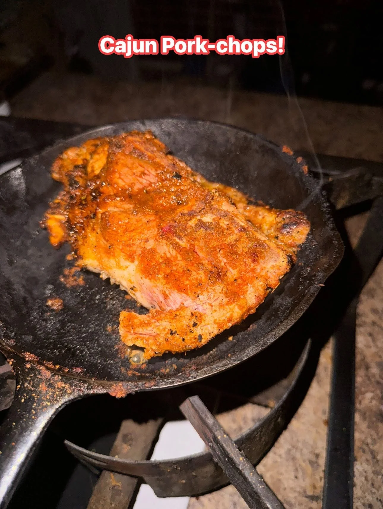Cajun-style pork chop sizzling in a cast iron skillet