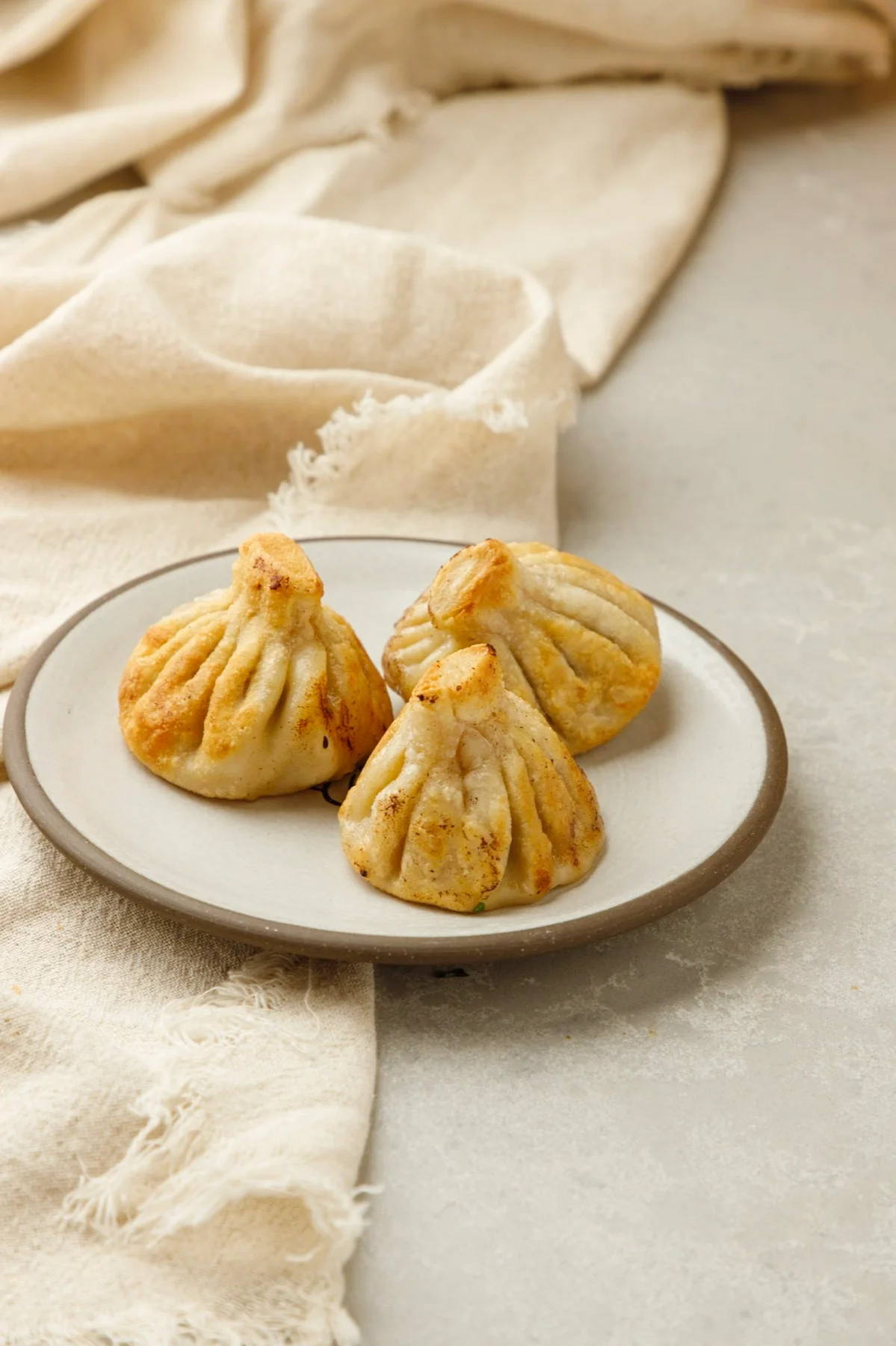 Pan-fried khinkali dumplings on a white plate