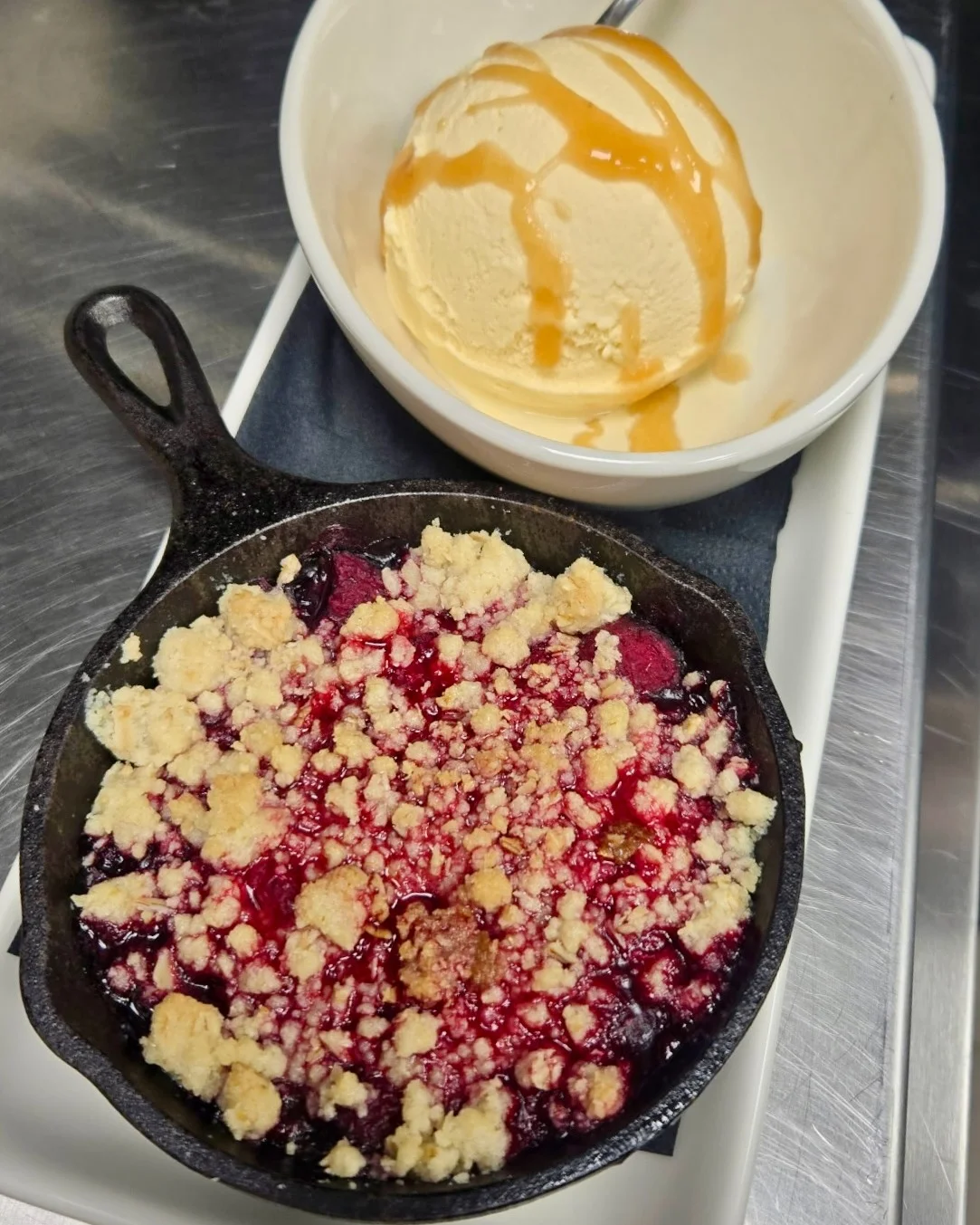 Warm berry crumble served in a cast iron skillet with vanilla ice cream