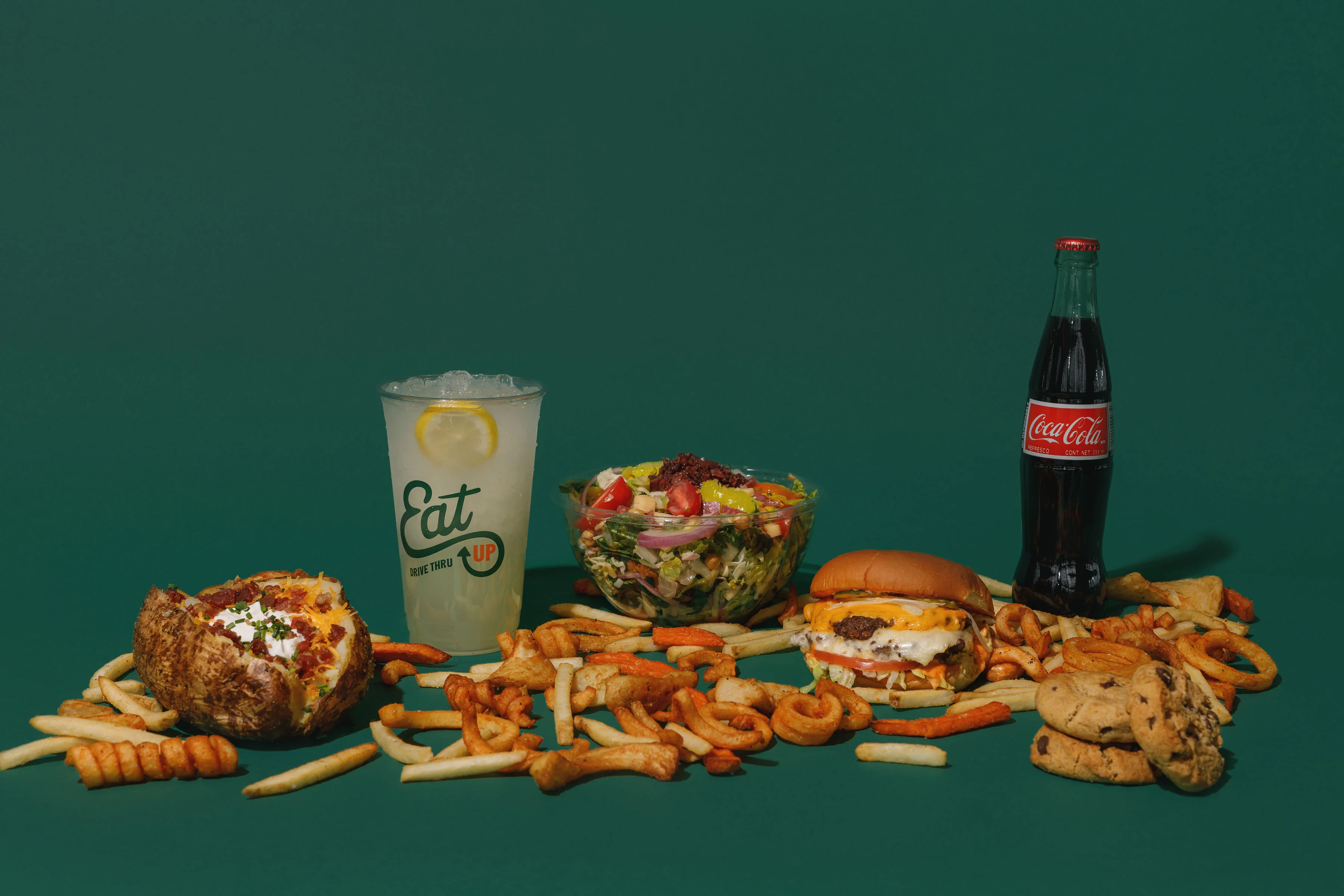 American cheeseburger with fries and salad on a green background