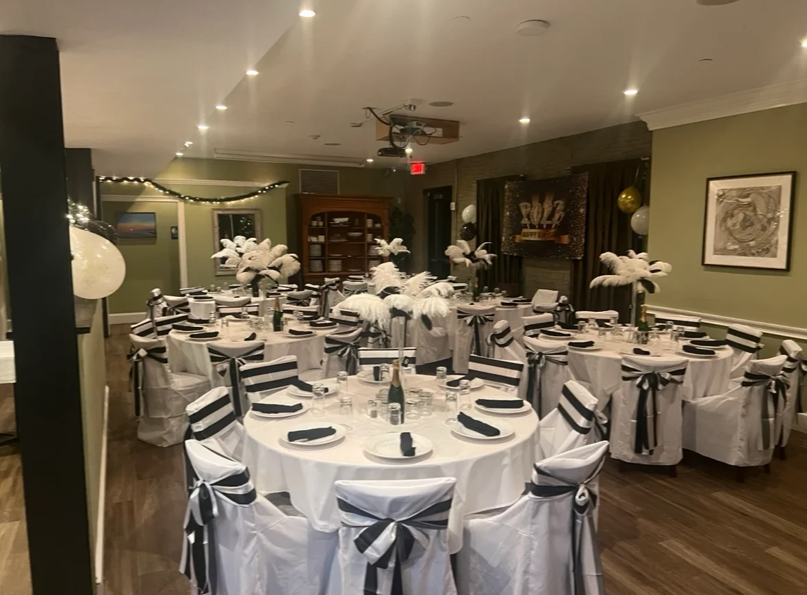 An elegantly set dining area with round tables adorned with black and white decor, ready for an event.
