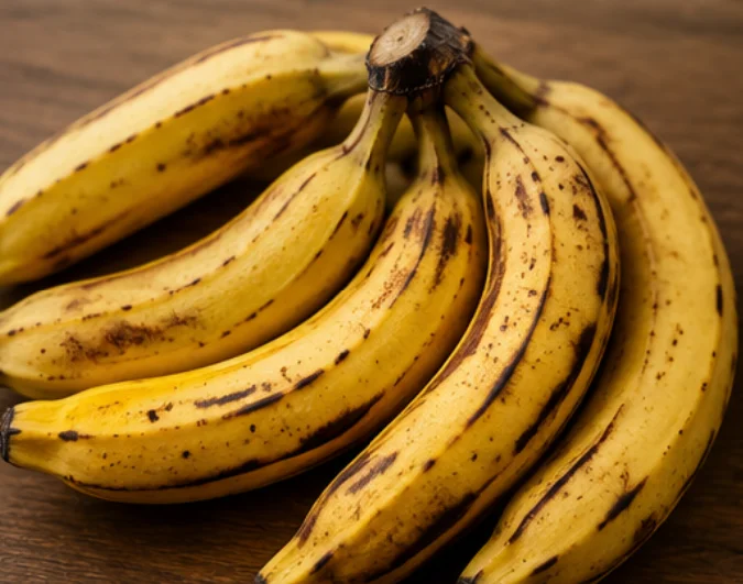 A bunch of ripe bananas on a wooden surface.