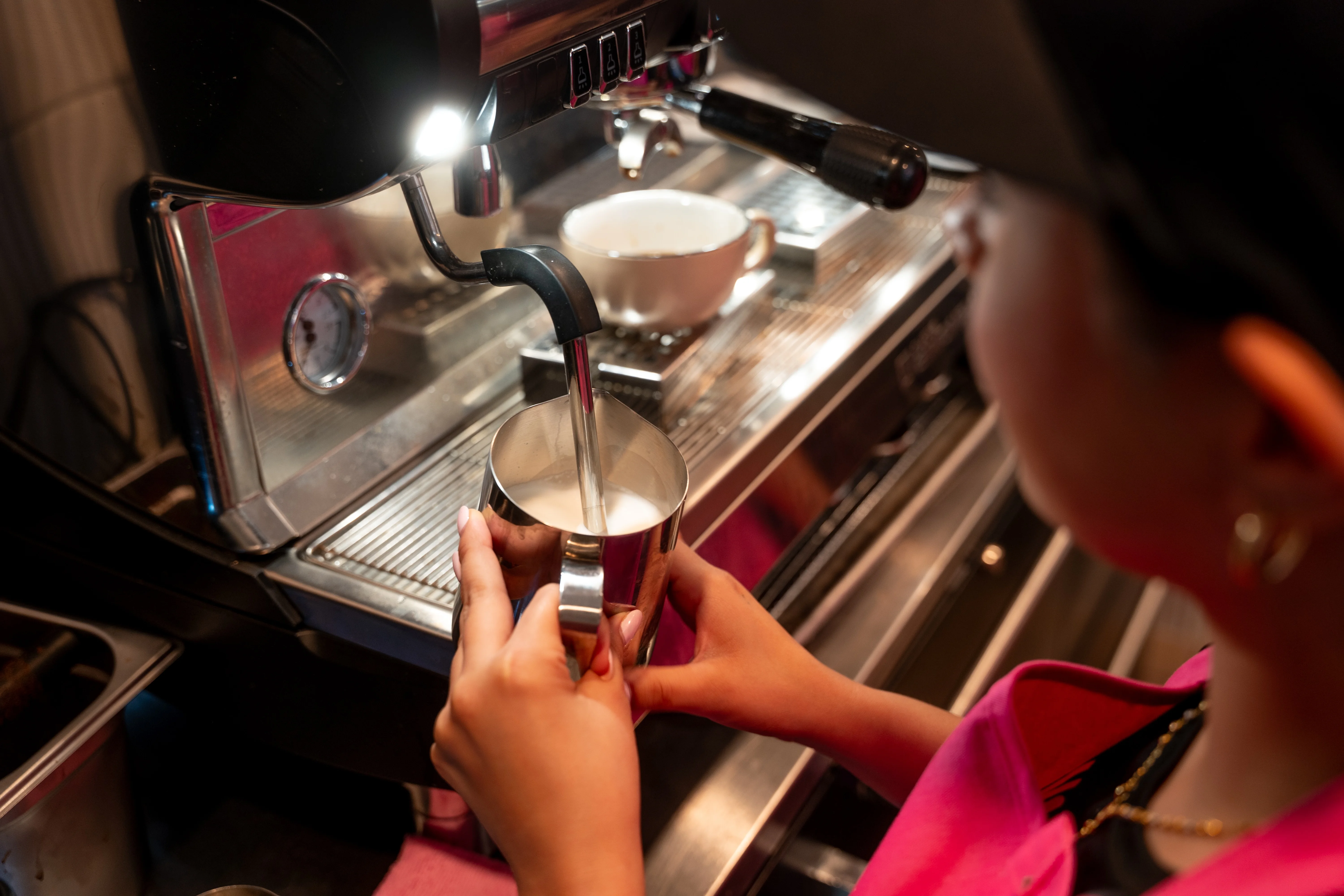 Barista steaming milk for coffee in a café