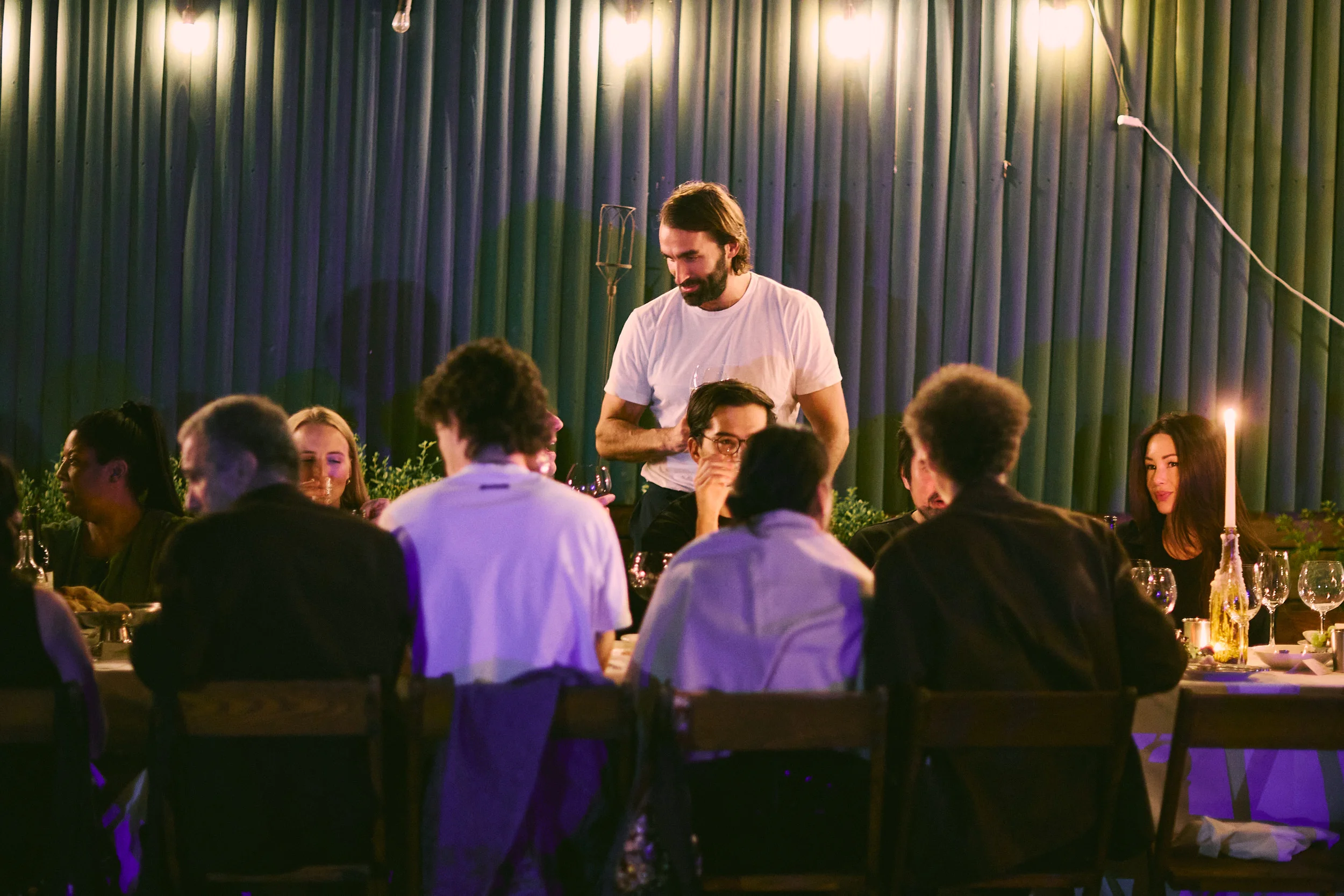 Lively restaurant dining room with guests and warm candlelit ambiance