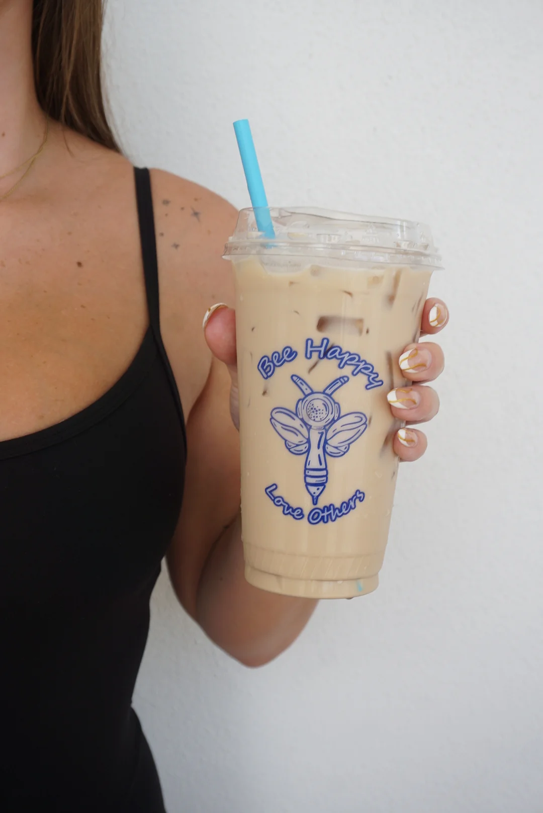 Iced coffee drink with a bee logo and blue straw