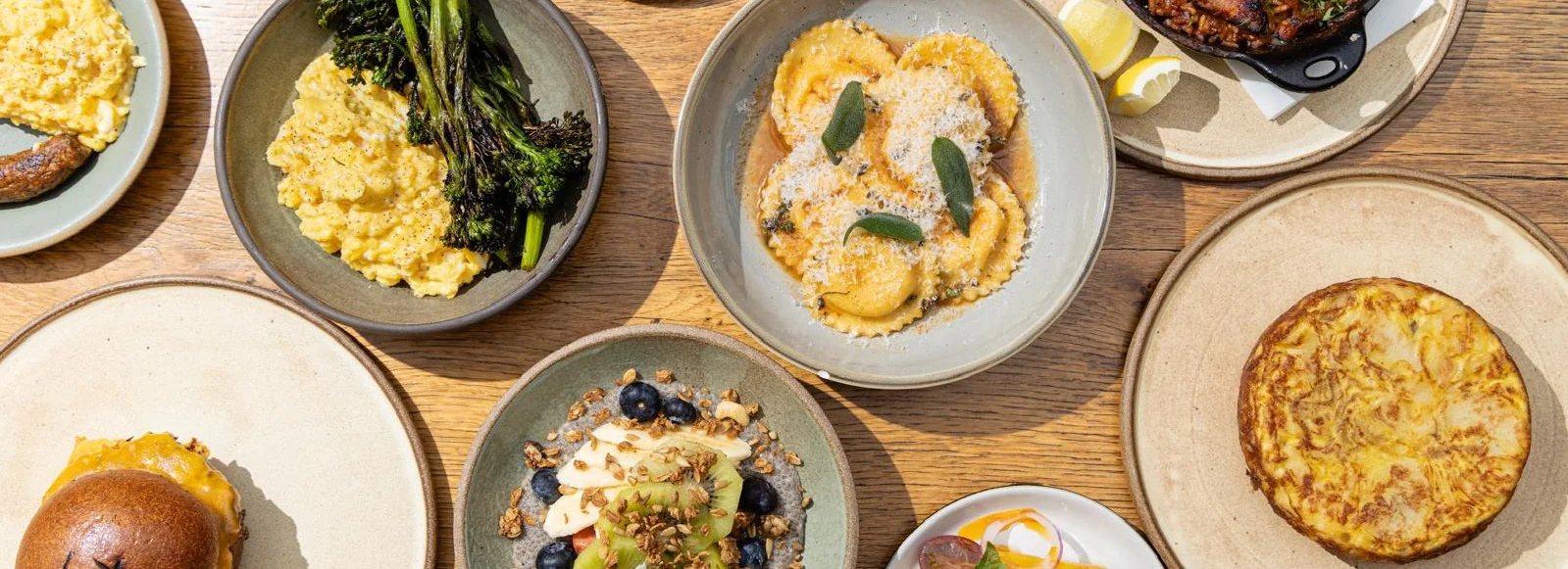 Assorted Italian dishes including ravioli and frittata on a wooden table