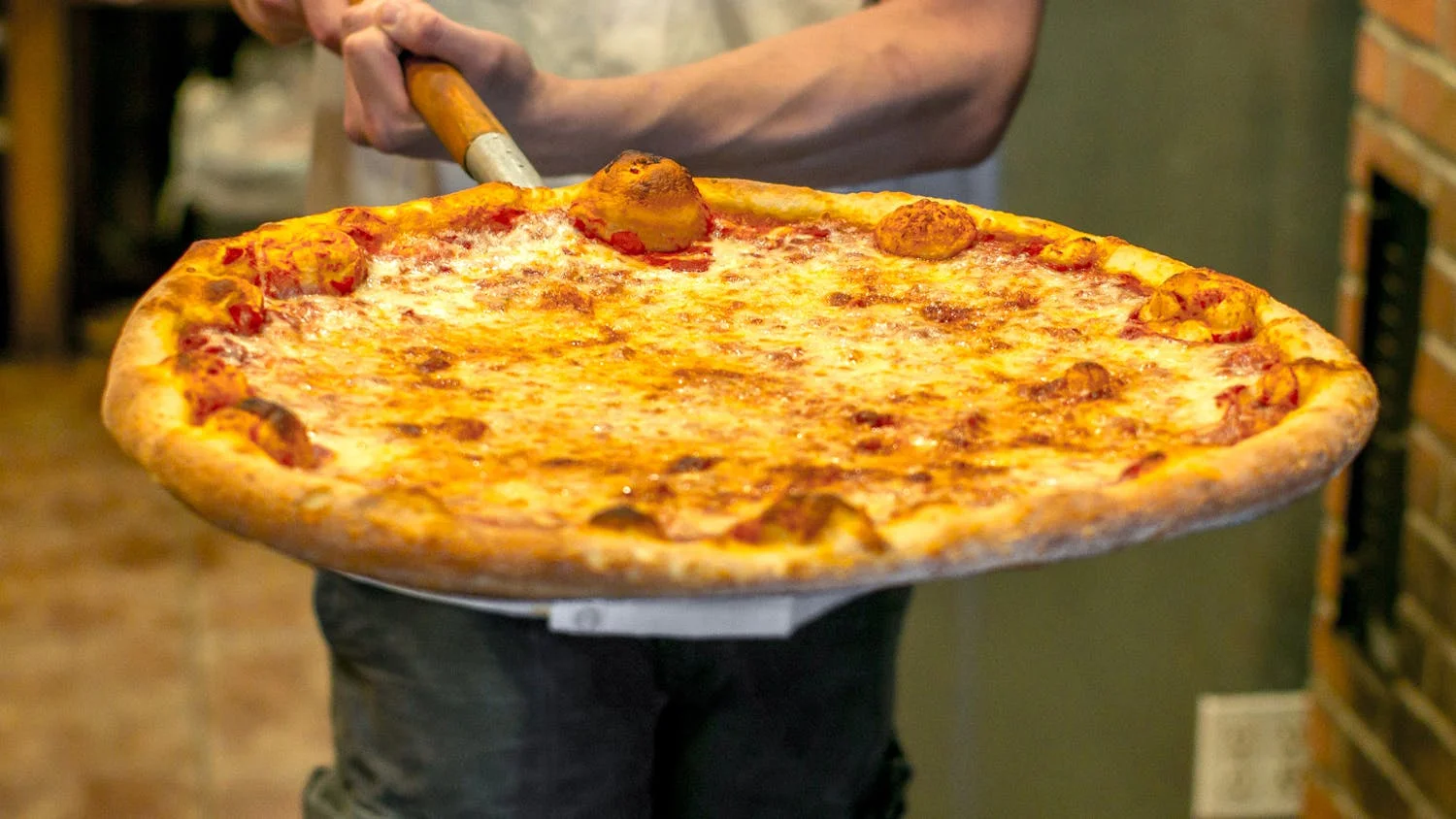 Freshly baked Margherita pizza served on a wooden peel