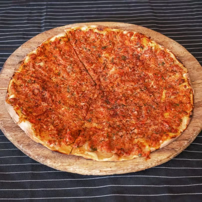 A large pizza with a crispy crust and a rich tomato topping on a wooden board.