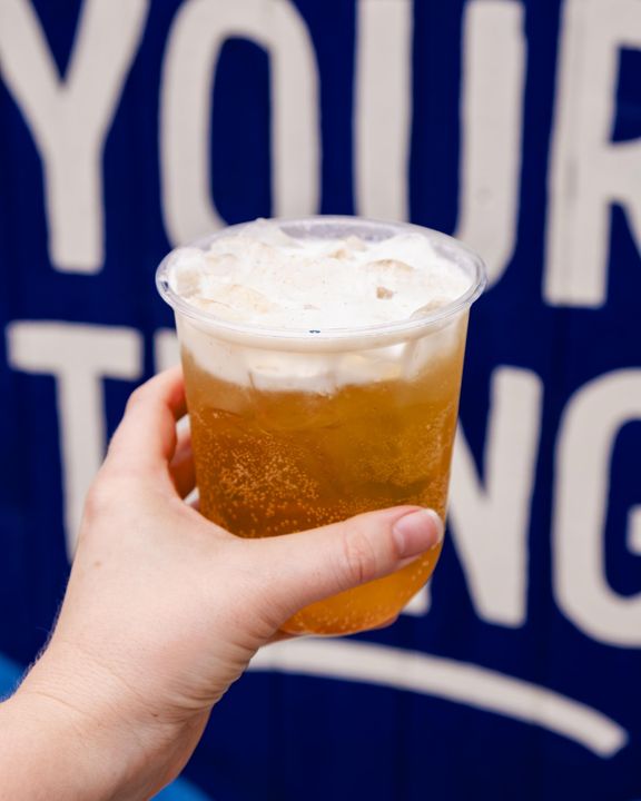 donut cider refresher held up in front of the mural