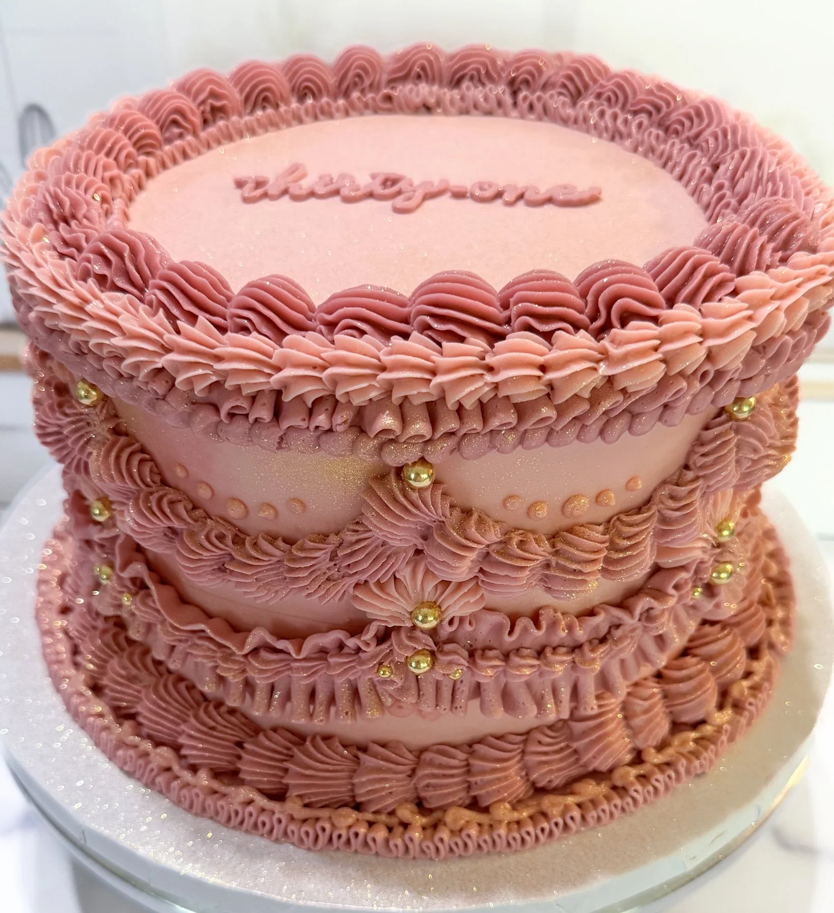 Elegant pink birthday cake with intricate frosting and decorative accents